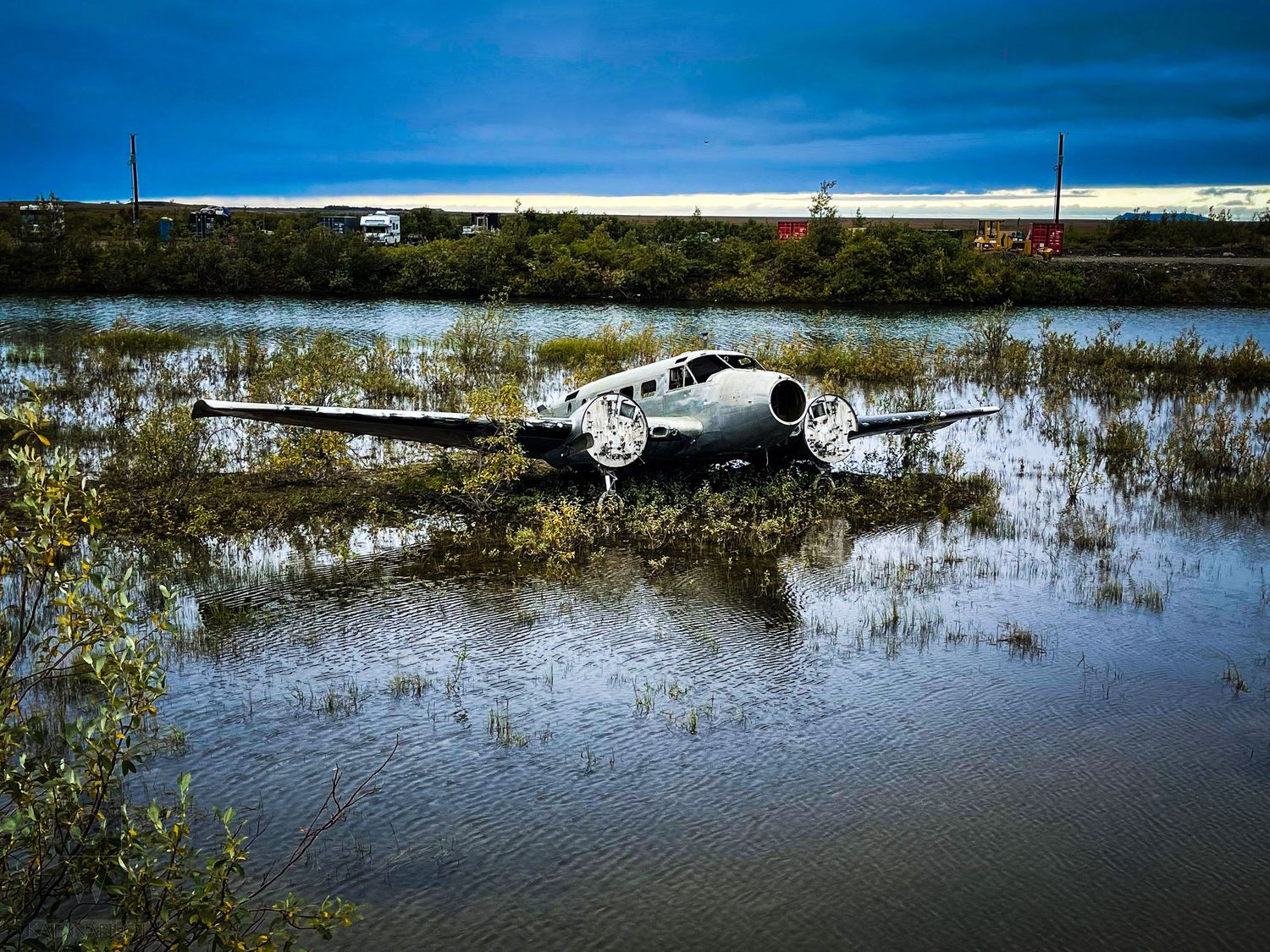 Panoramic view of flooded landscape with small aircraft visible in the distance.