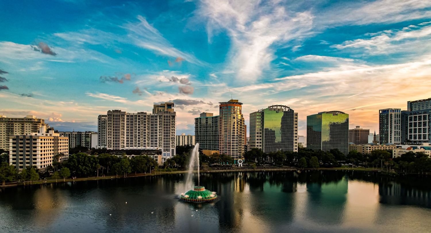 Panoramic cityscape of downtown Orlando reflecting in Lake Eola during sunset.
