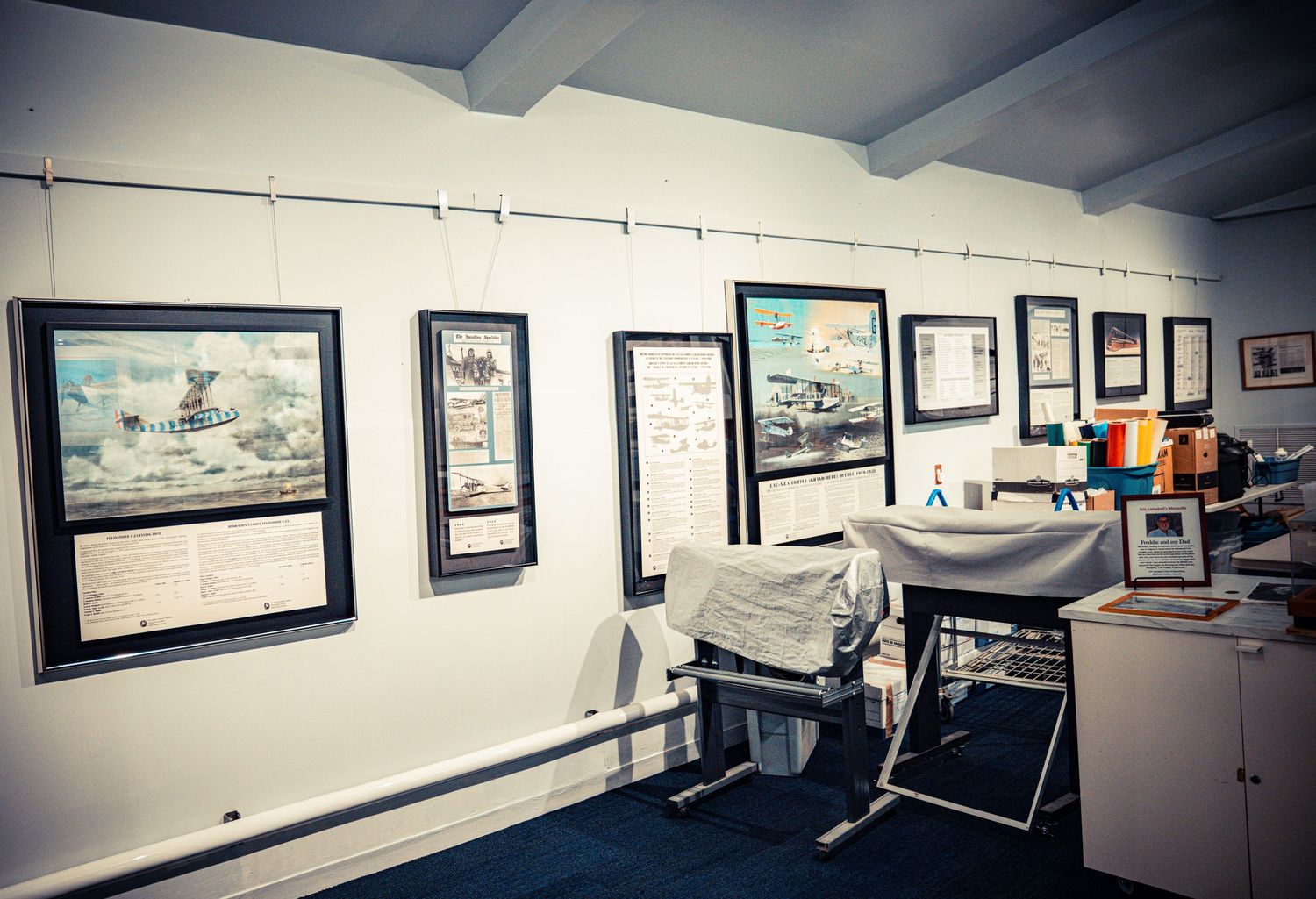 Museum wall displaying framed aviation artwork and historical photographs.