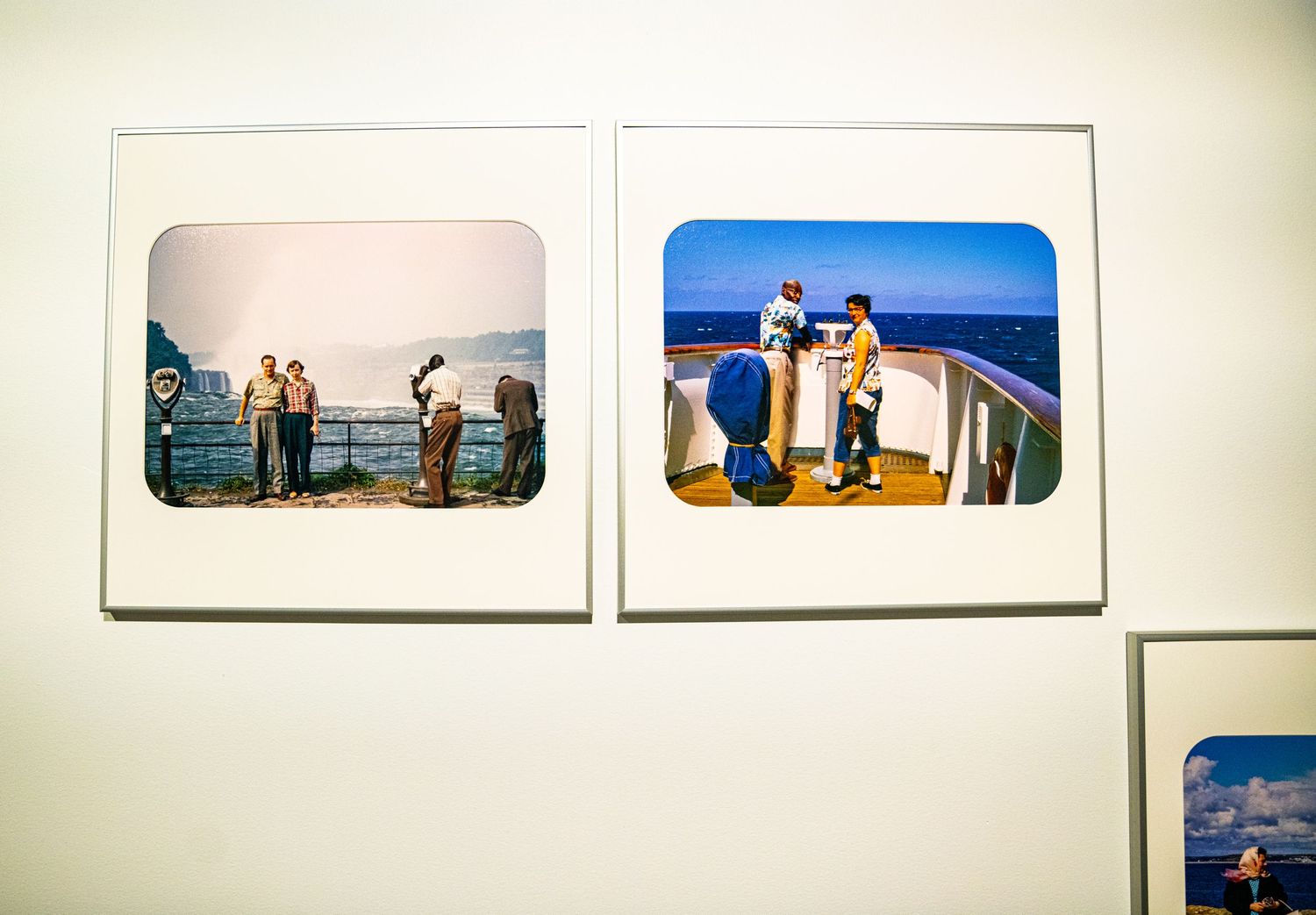 White gallery wall with mounted photographs showing outdoor scenes and landscapes.