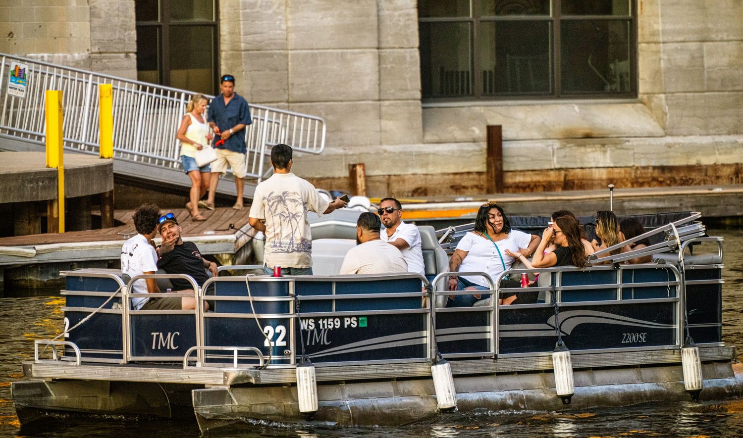 Waterfront deck with railings and boats moored alongside.