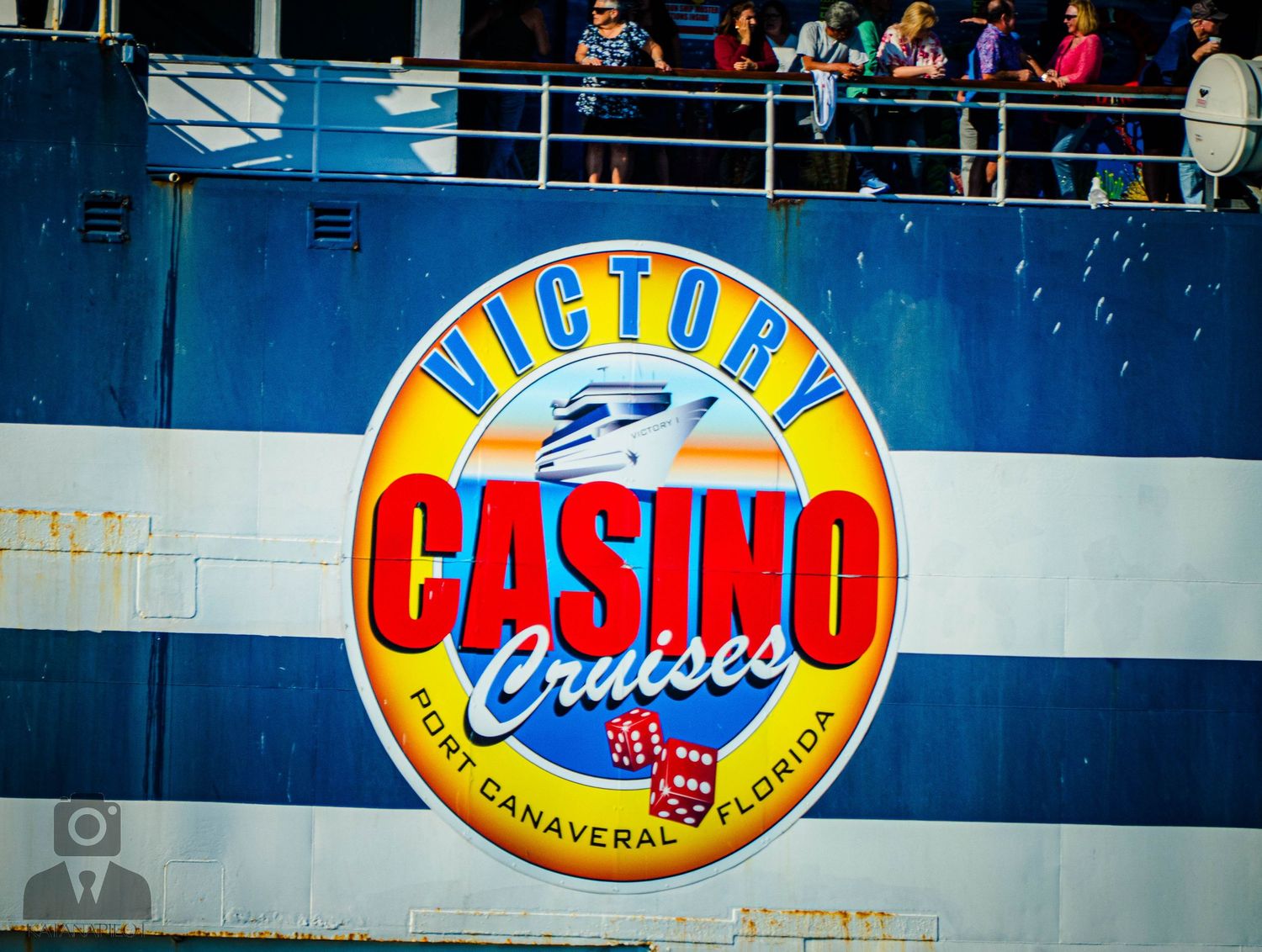 Colorful Victory Casino Cruises logo painted on blue ship hull featuring dice and playing card graphics.