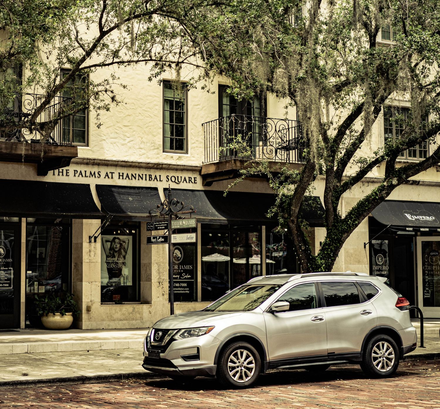 Silver Nissan Rogue SUV parked outside The Palms at Hannibal Square boutique in a scenic Southern town with Spanish moss trees.