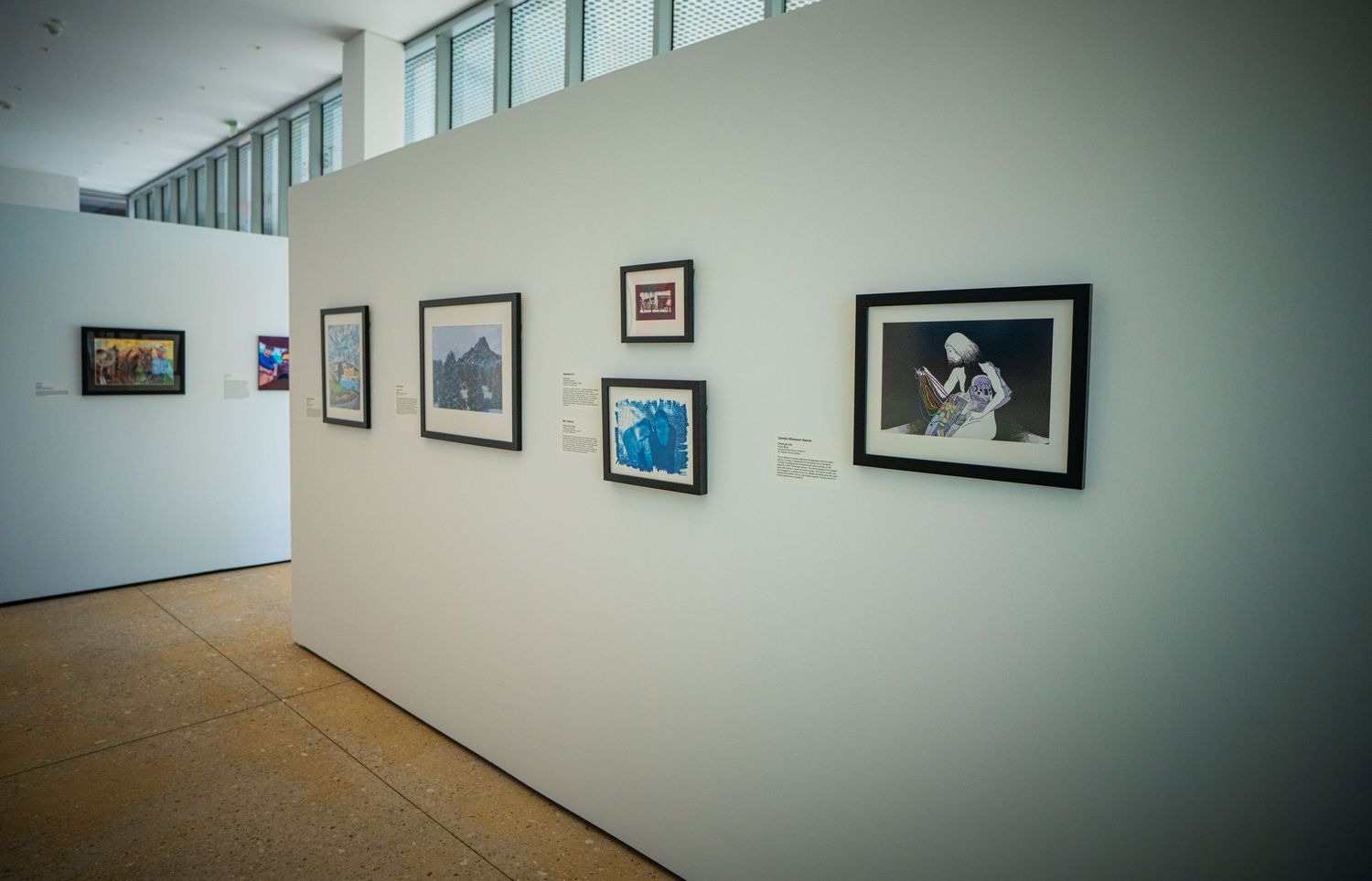 Contemporary art gallery space with black and white photographs mounted on light gray walls.