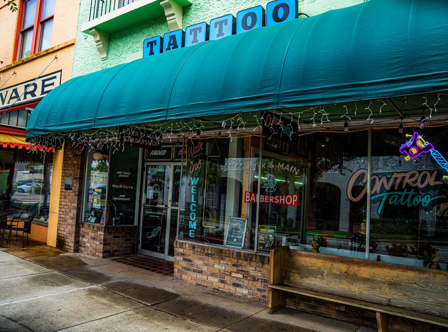 Row of retail storefronts with turquoise awnings along a commercial street.