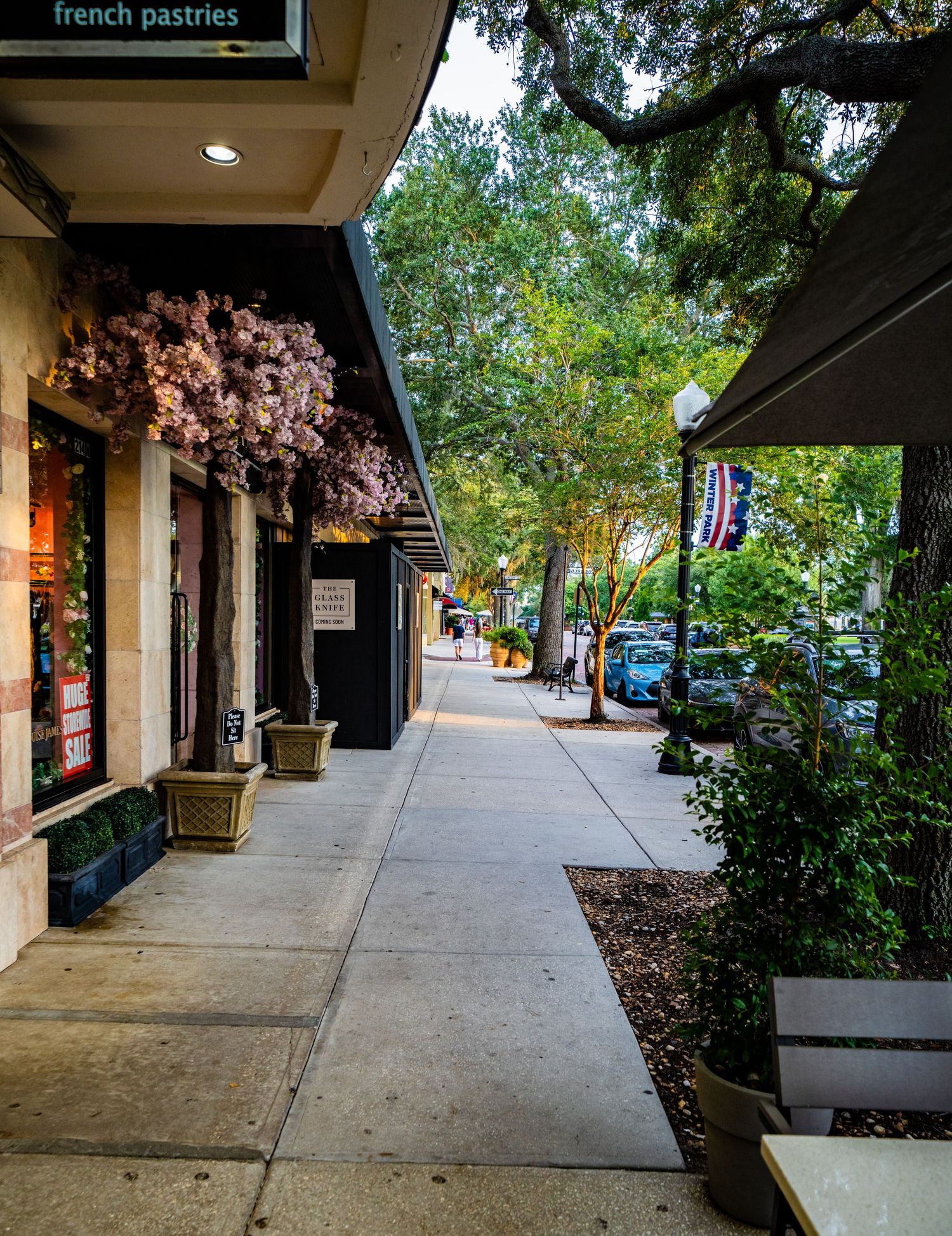 Wide brick sidewalk with covered walkway and storefronts in a shopping district.