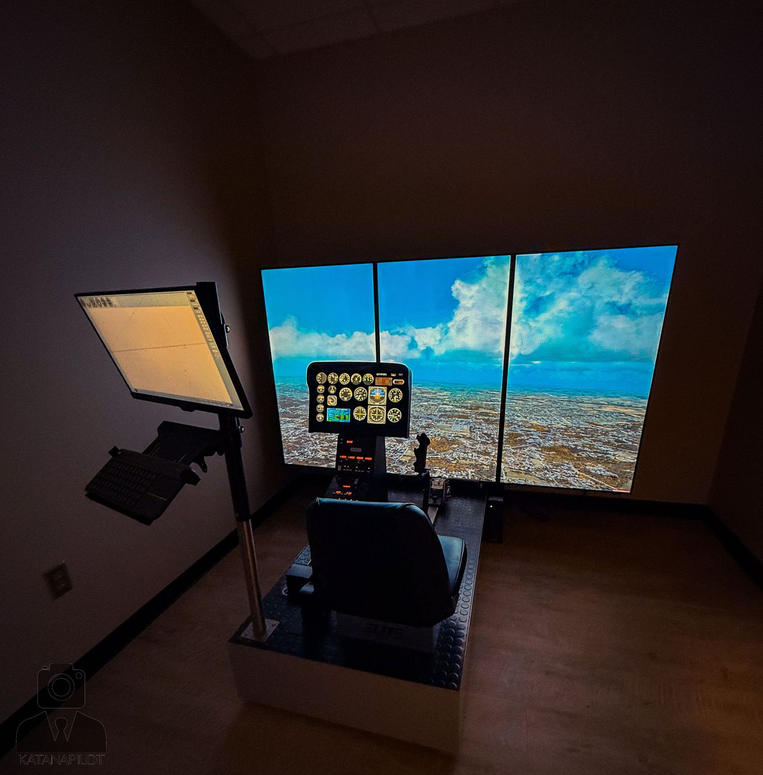 Flight simulator setup with multiple screens displaying aerial views in a dark room.