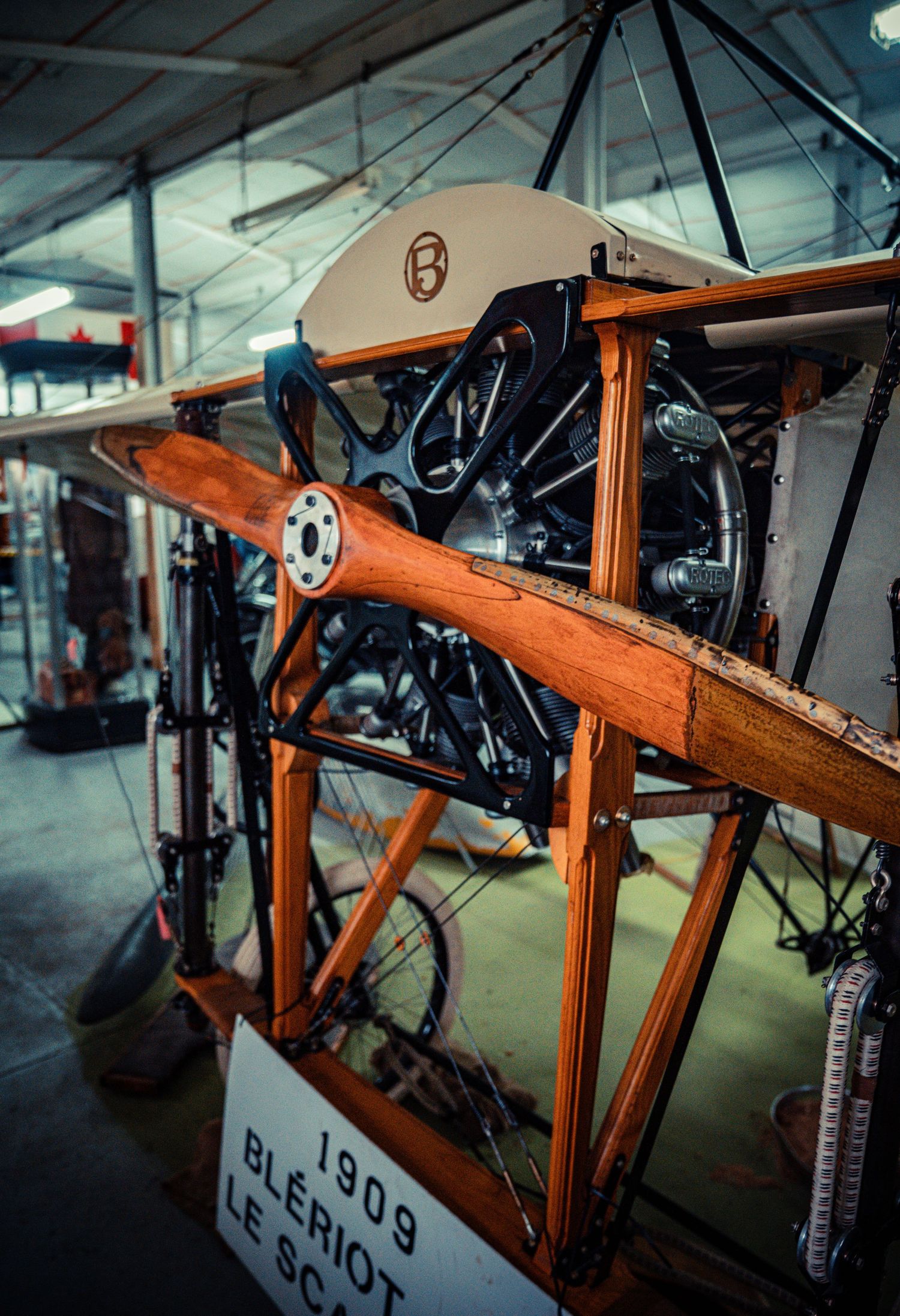 Close-up of a vintage biplane engine and wooden propeller in museum display.