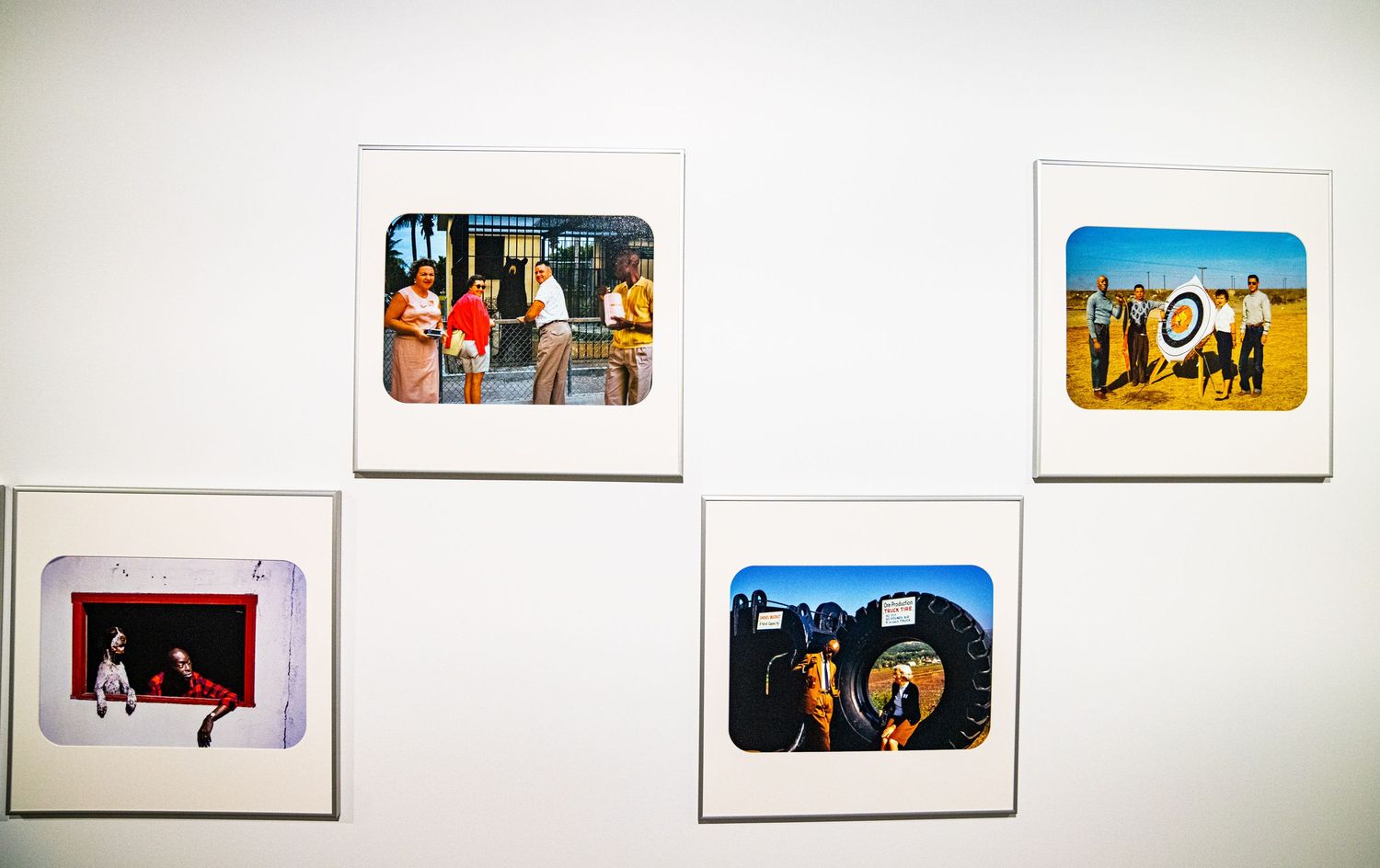 Art gallery installation with multiple framed photographs arranged in a horizontal line.