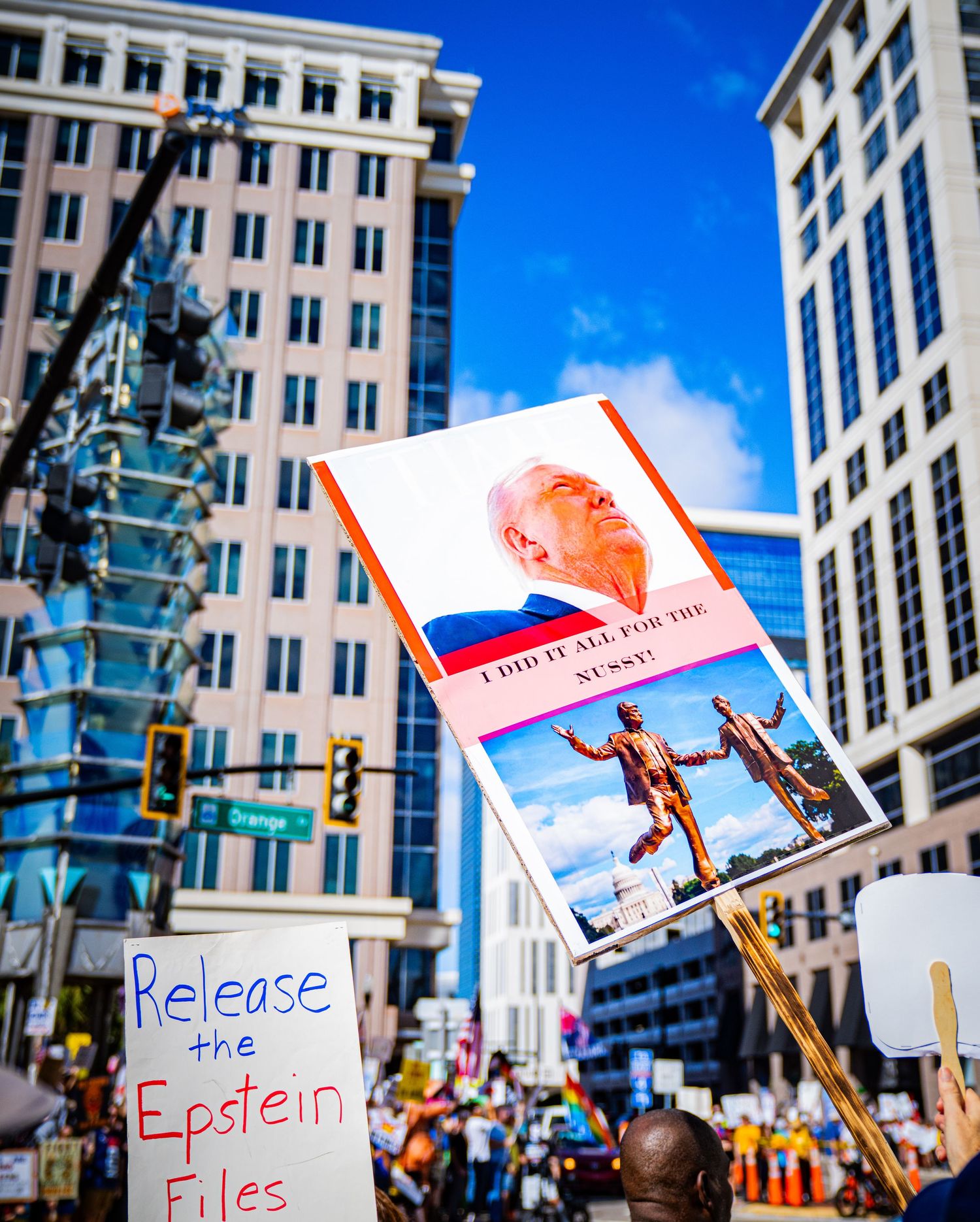 Protest signs against a backdrop of modern office buildings and blue sky.