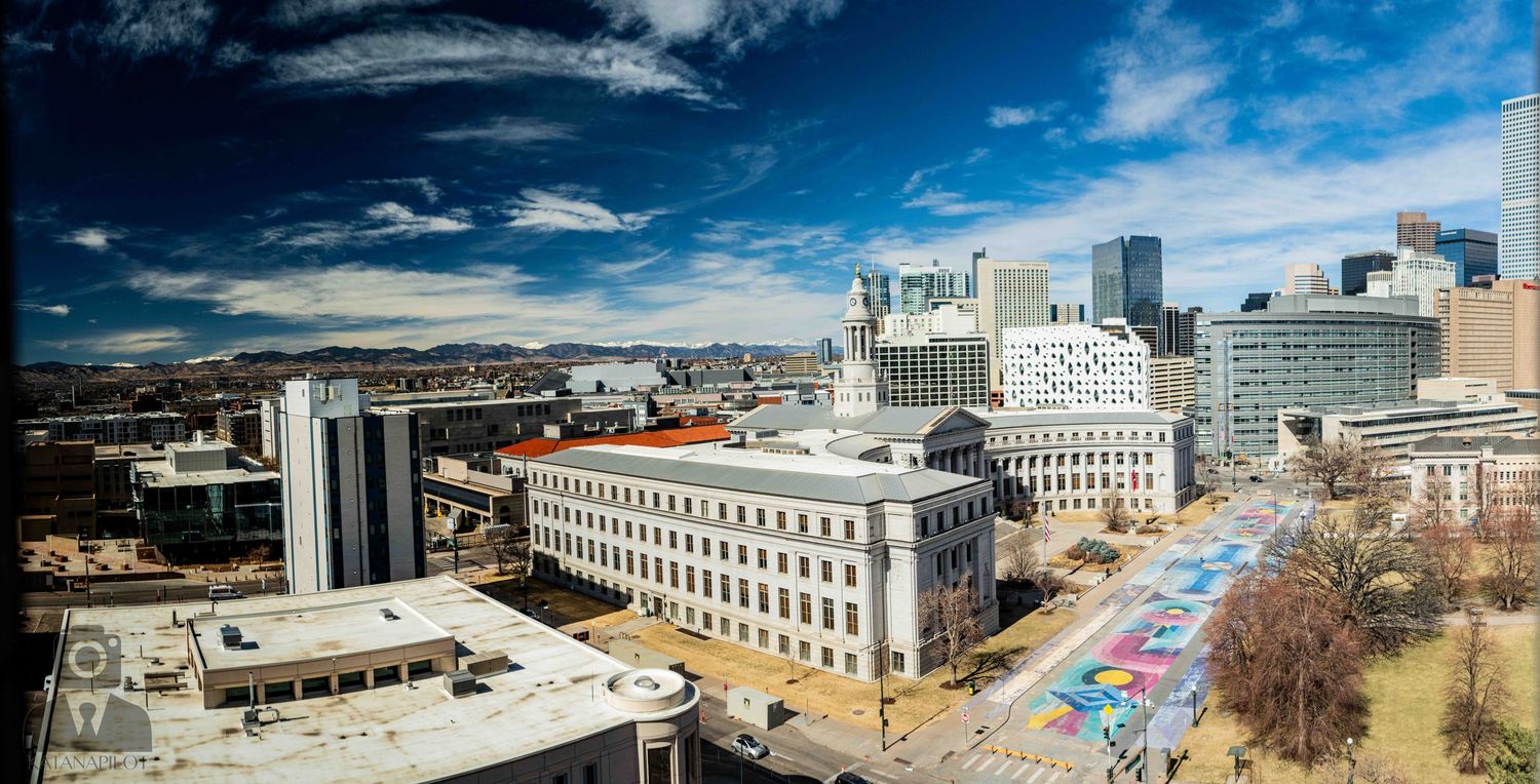 Panoramic aerial view of downtown Montreal cityscape with modern buildings and streets under bright blue sky.