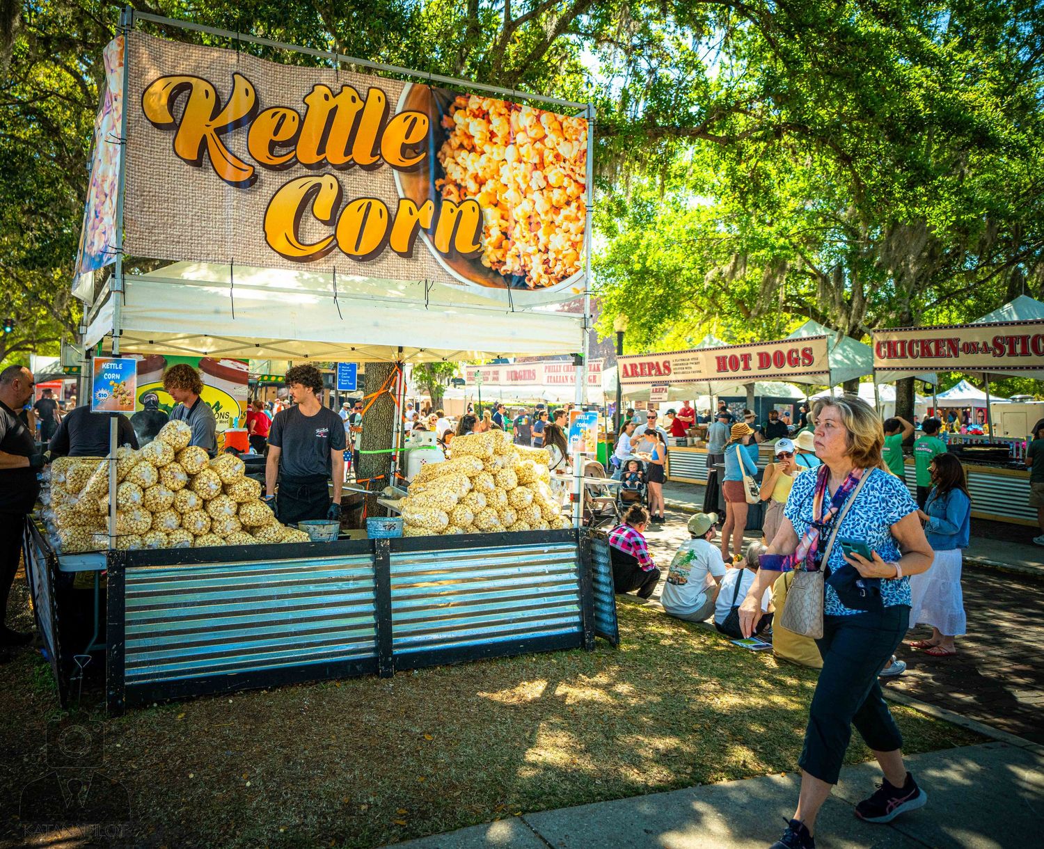 Outdoor festival food vendors with kettle corn and concession stands serving customers.