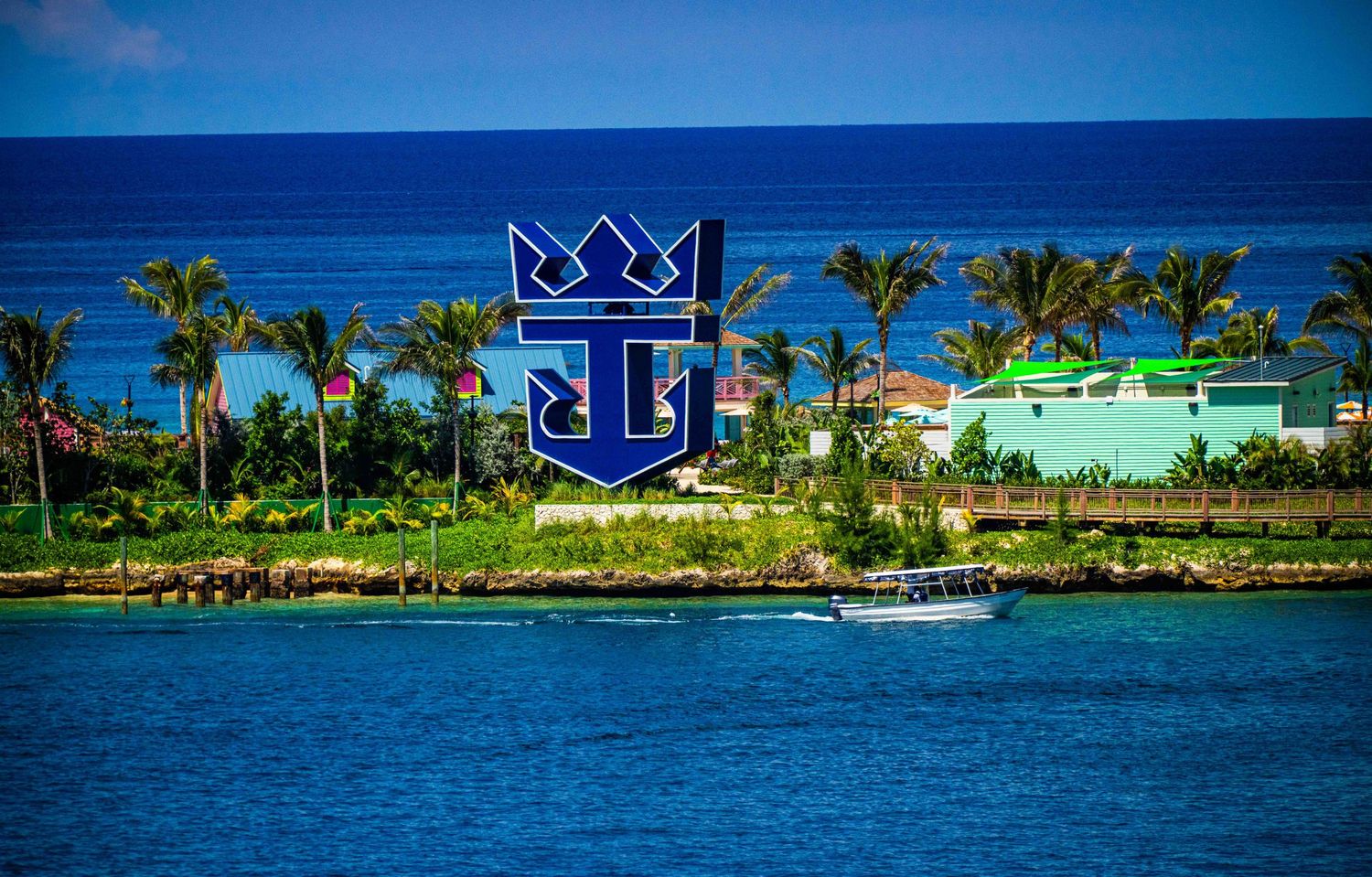 Royal Caribbean cruise line logo displayed near a tropical island port with palm trees and turquoise ocean waters.