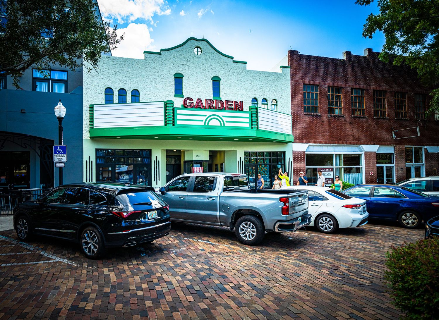 Row of retail shops and businesses with vintage-style architecture and parking area.
