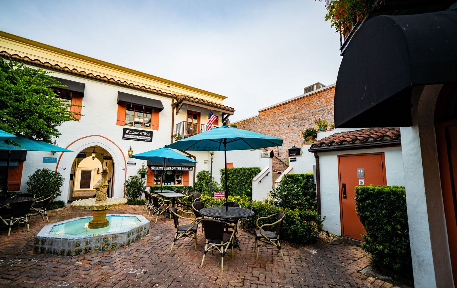 Mediterranean-style shopping courtyard with terra cotta roofs and outdoor seating areas.