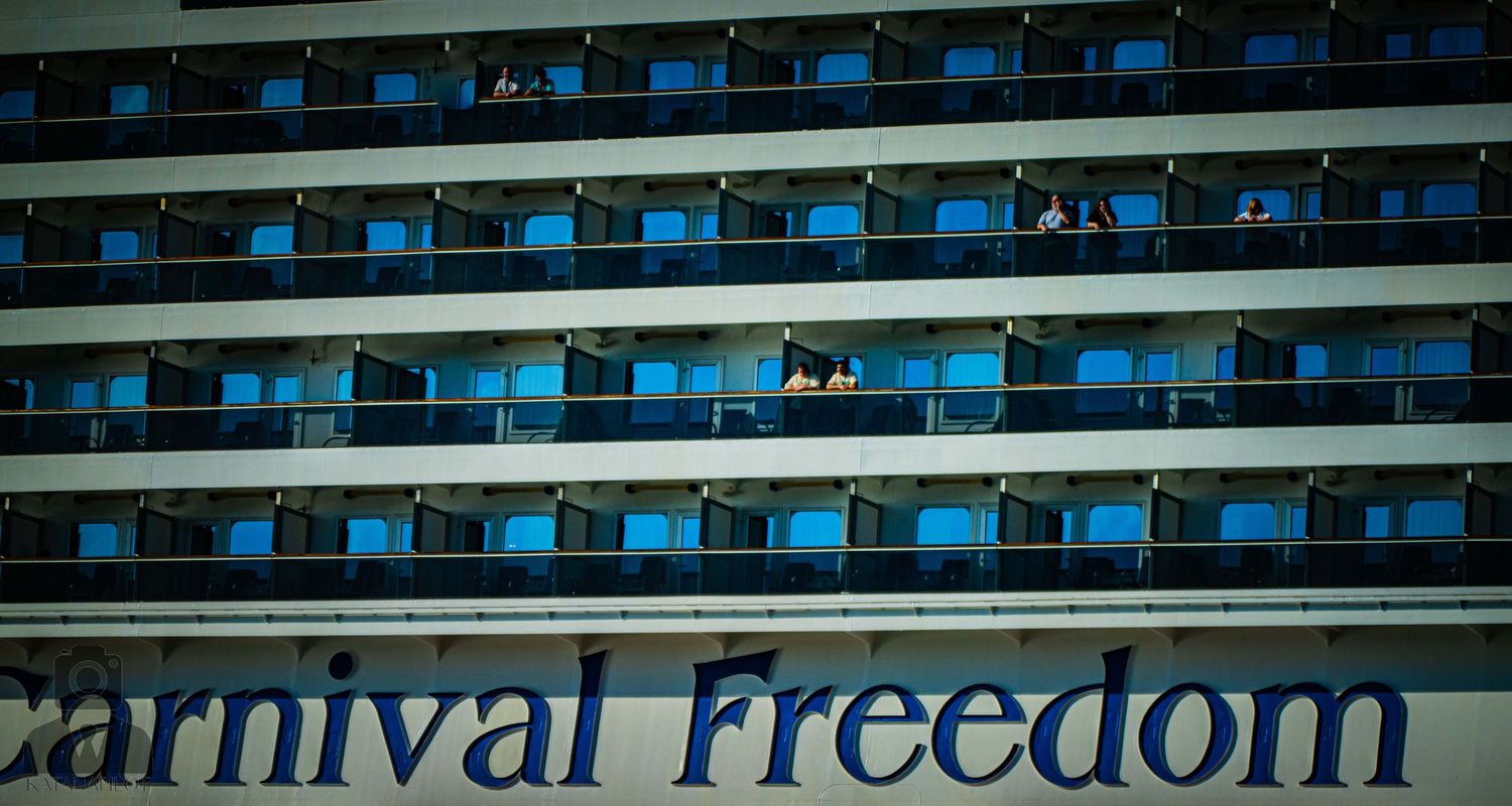 Carnival Freedom cruise ship name displayed in blue text on white hull of vessel.