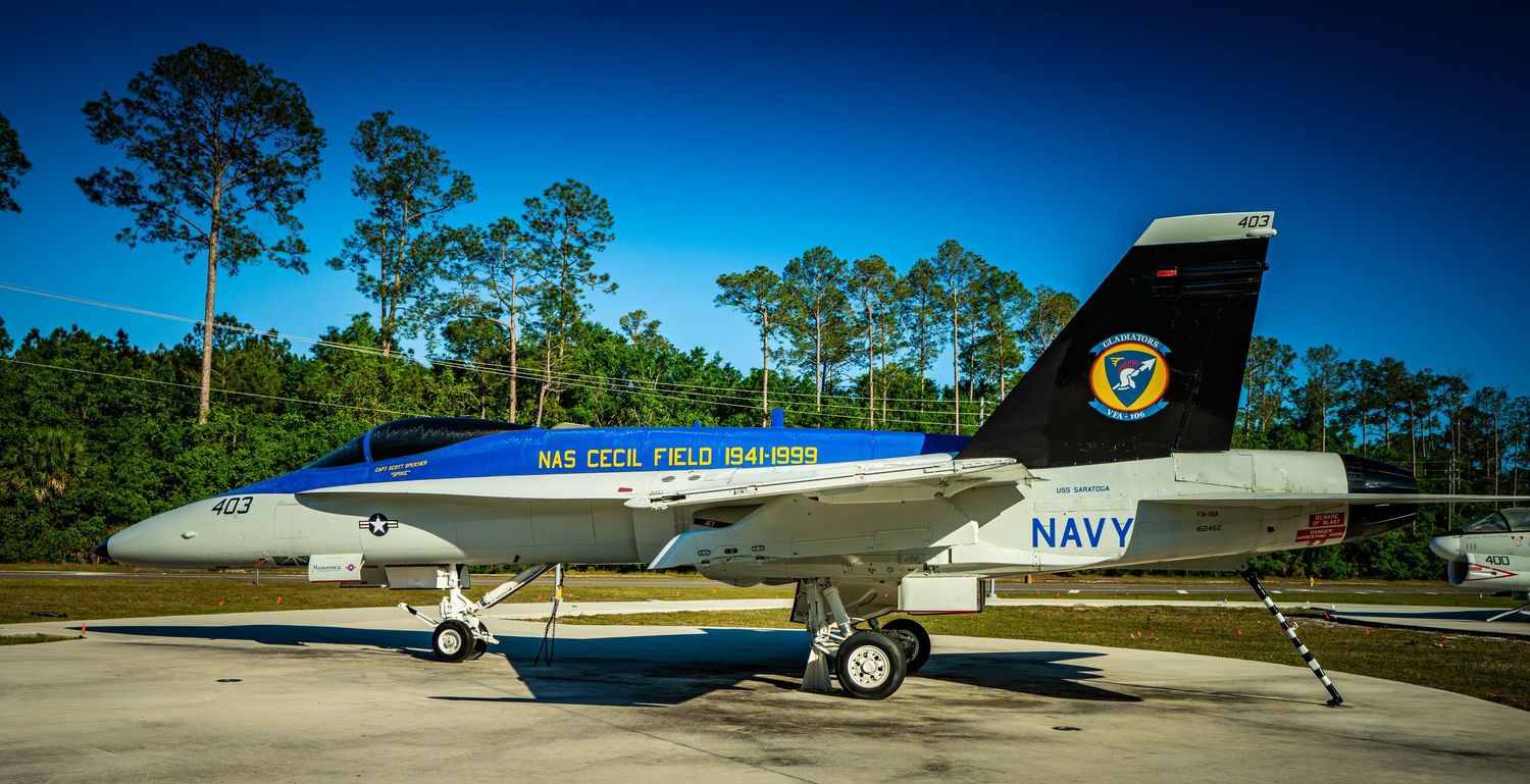 A Navy F/A-18 Hornet jet on display at NAS Cecil Field under a clear blue sky.