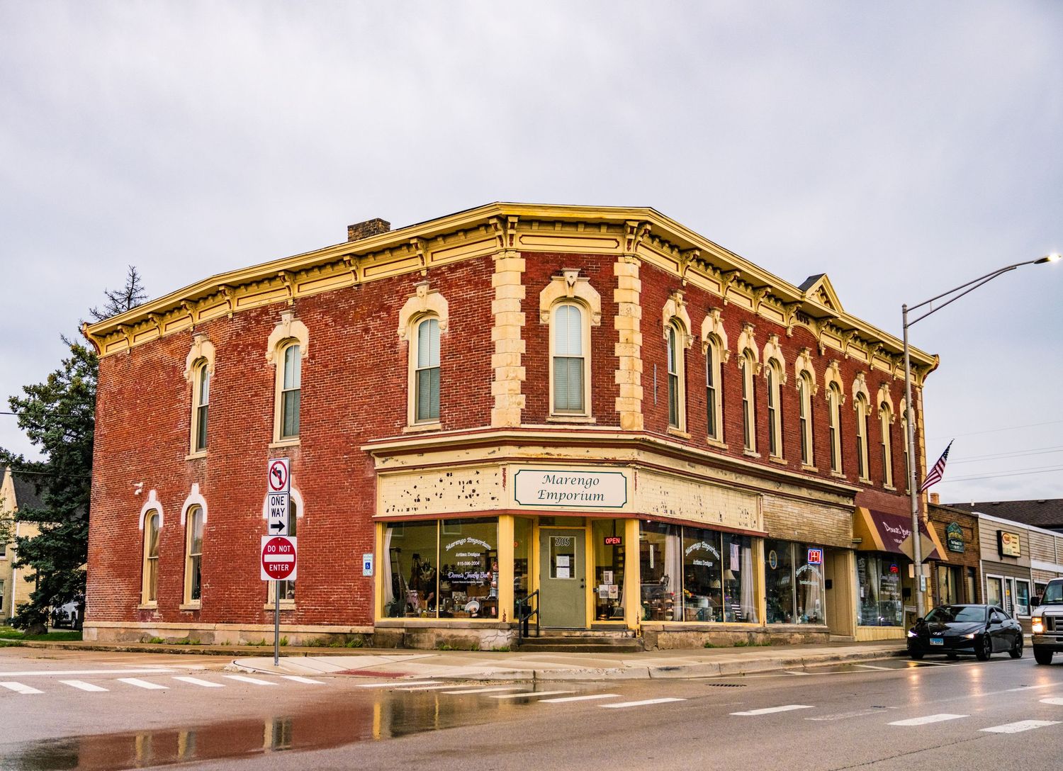 Red brick commercial buildings with classic architectural details along a small town intersection.