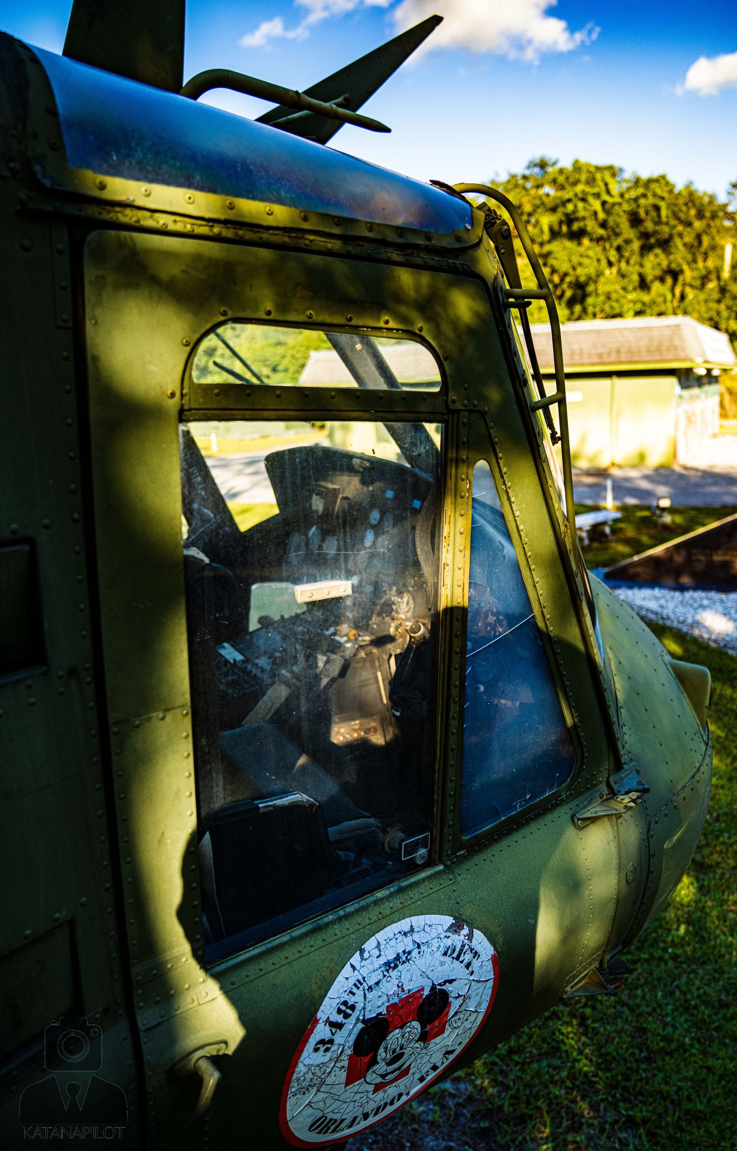 Weathered military helicopter cockpit windows with faded markings visible in natural lighting.