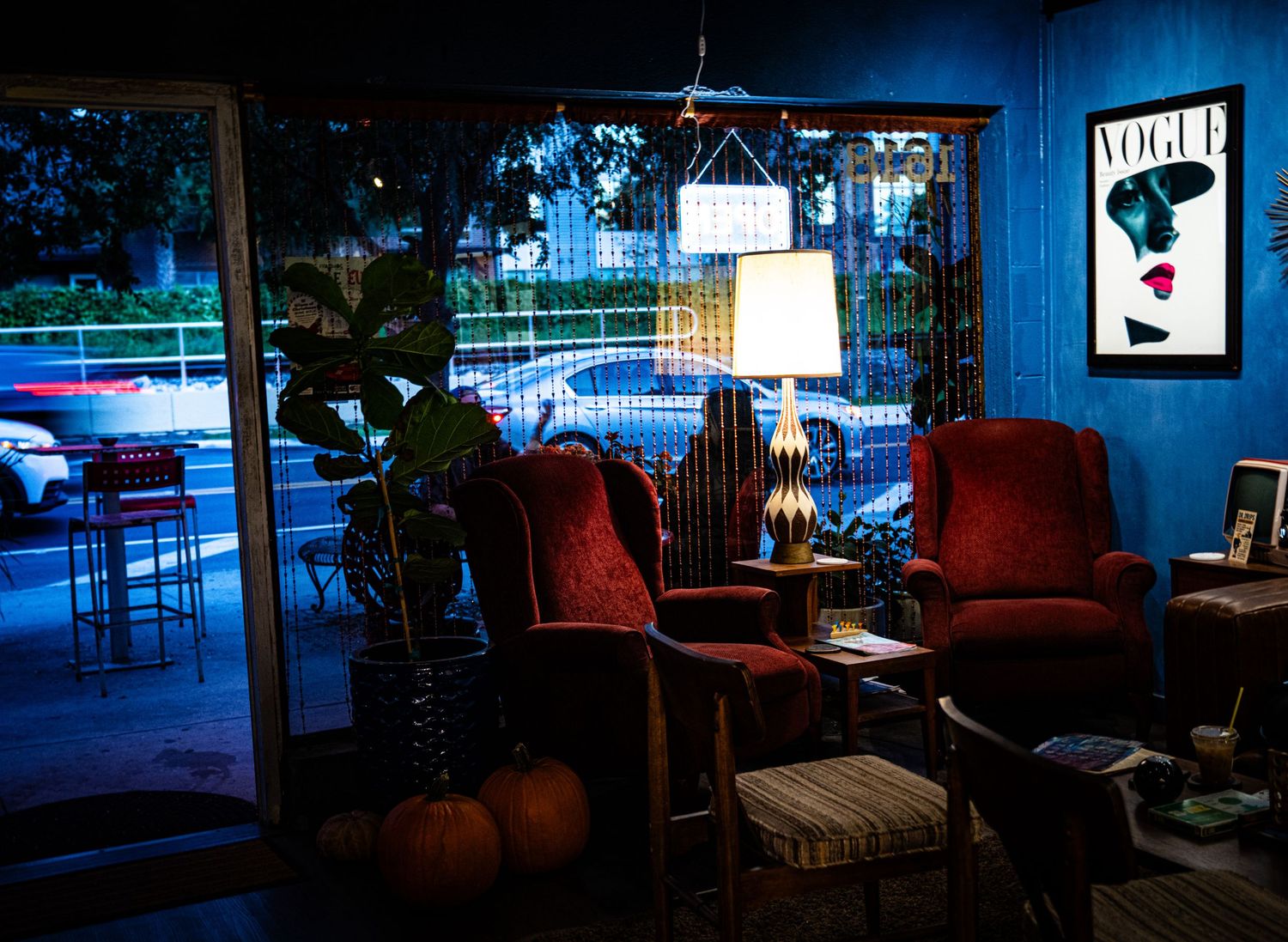 A panoramic view of a modern lounge area with red chairs and blue lighting in an evening setting.