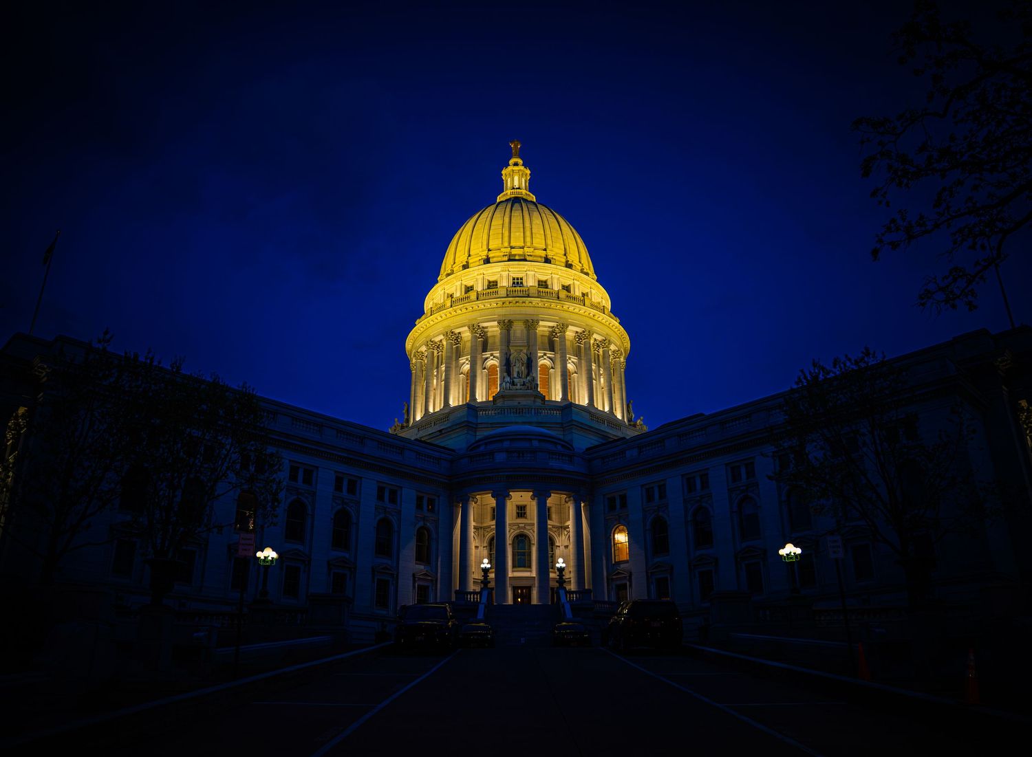 Wisconsin State Capitol building illuminated in golden light against a deep blue twilight sky.