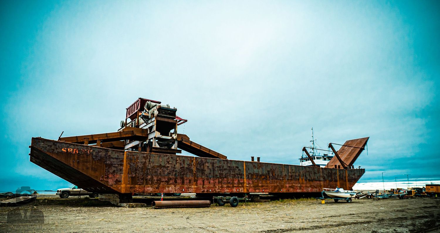 Abandoned rusty shipwreck on beach stretching across panoramic view.