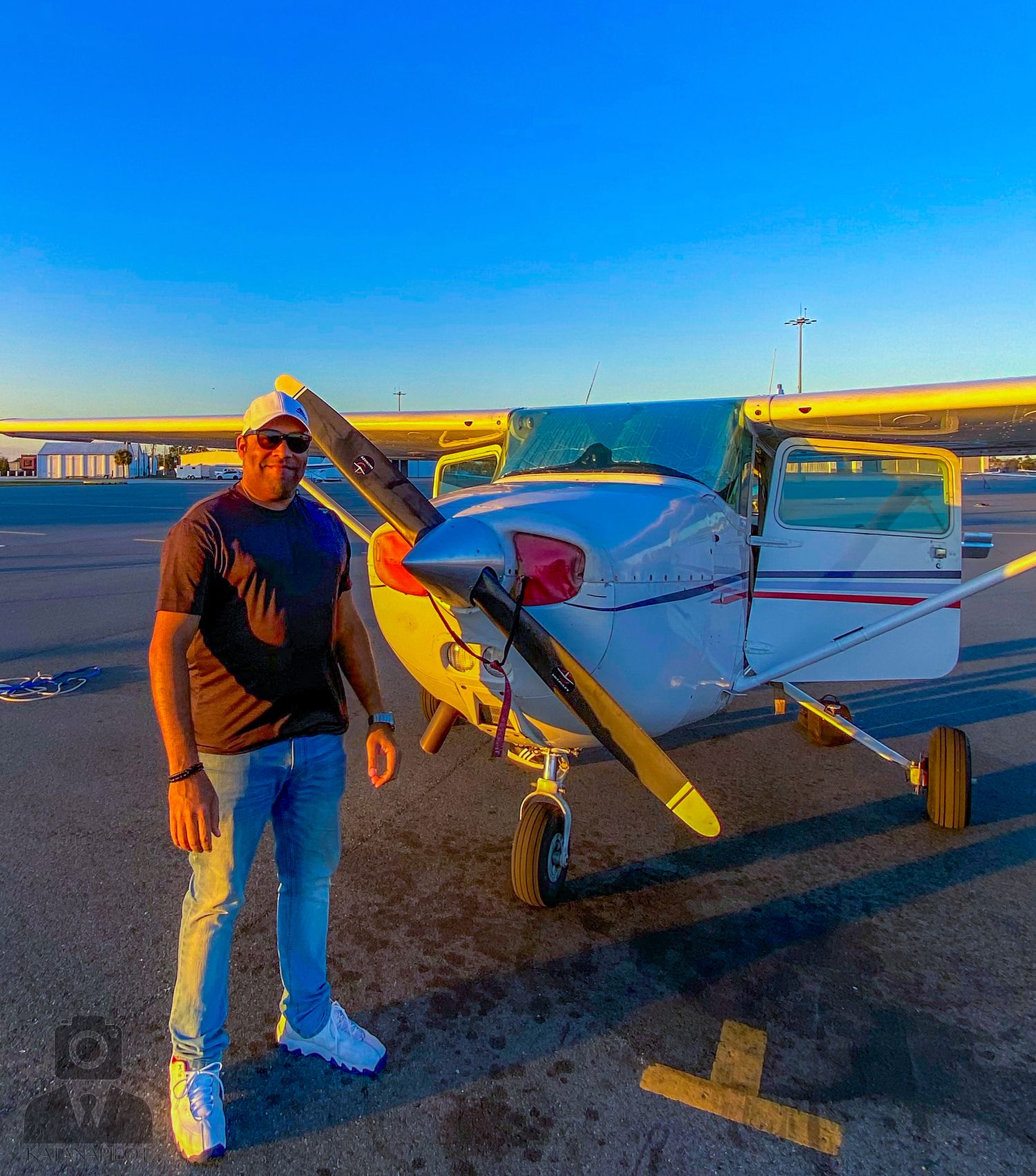 Small yellow and white aircraft parked on an airport ramp at sunset.