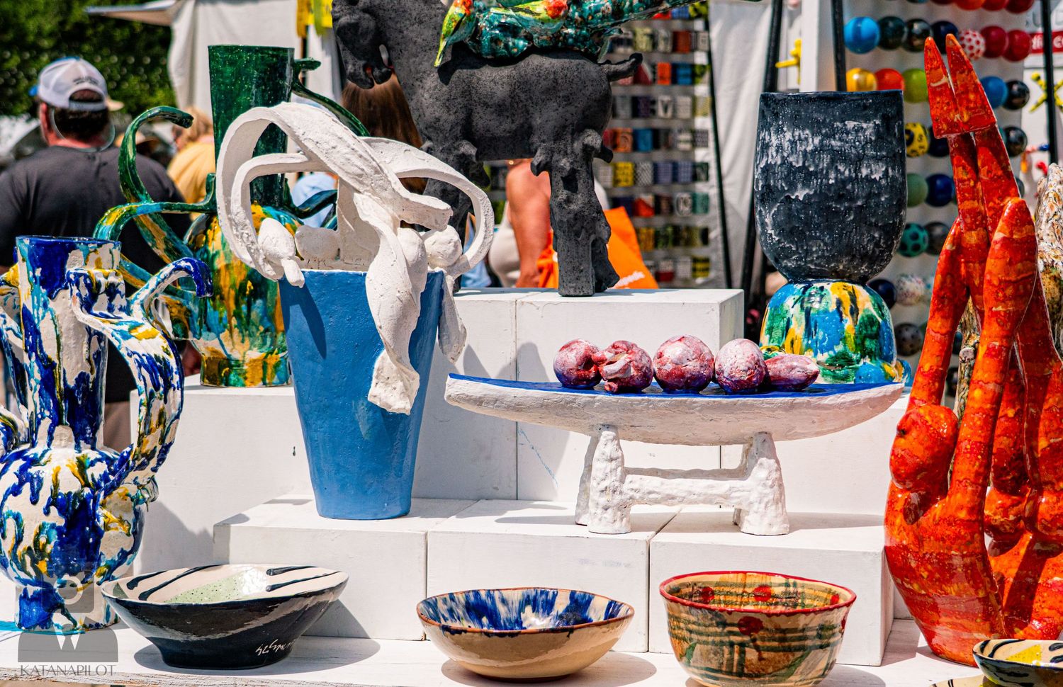 Colorful handcrafted pottery and ceramics displayed at an outdoor art festival market.