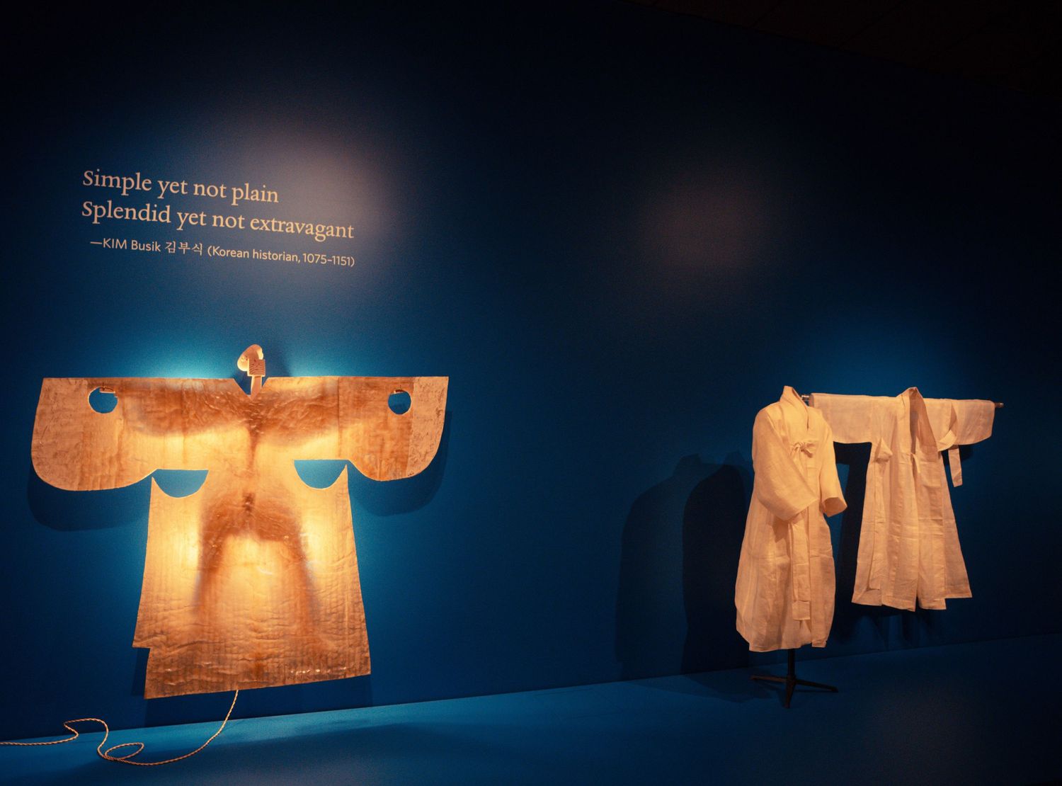 Illuminated text-based art installations glowing against dark blue walls in an exhibition space.