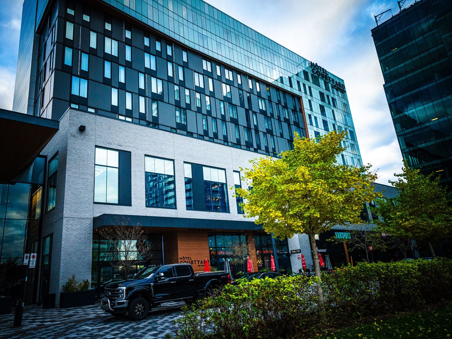 Modern glass office buildings with curved facades surrounded by autumn trees.