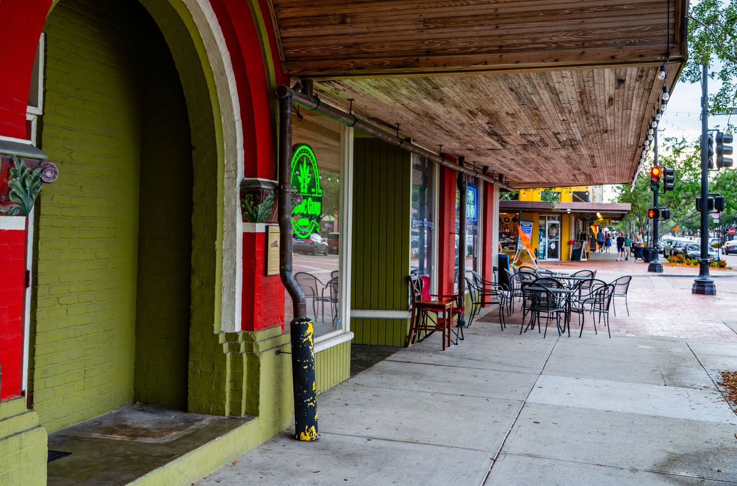 Historic storefront architecture with red and green painted walls and covered sidewalk.
