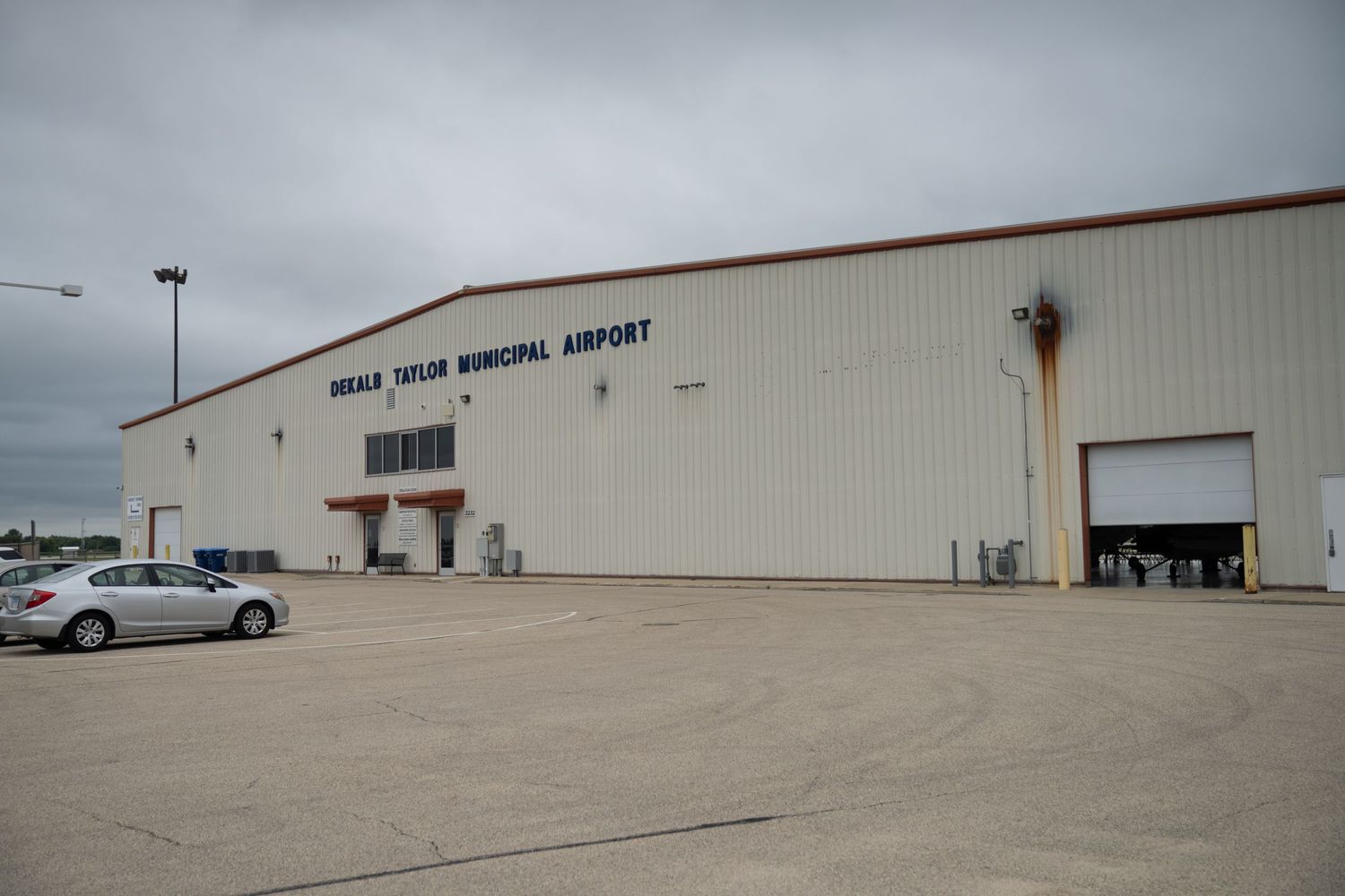 Long exterior view of a municipal airport terminal building with empty parking lot.