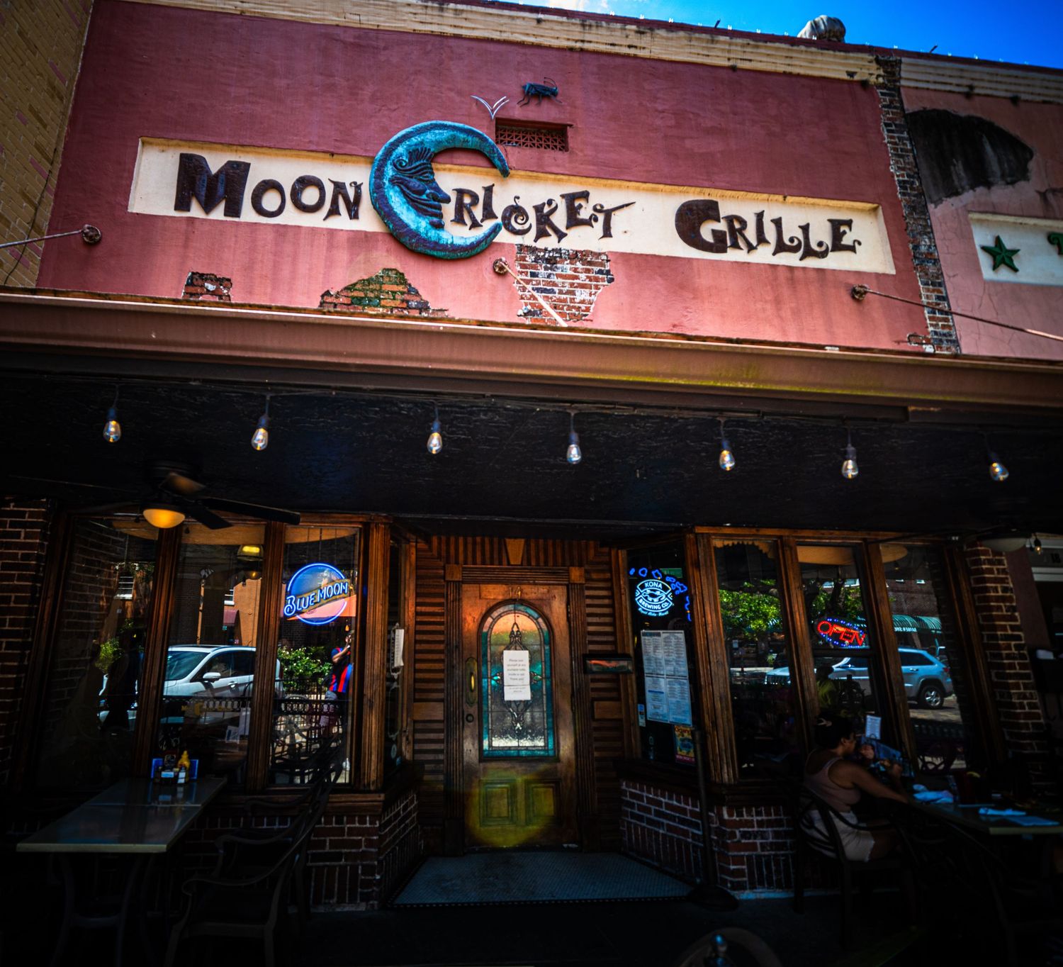 Exterior view of Moon Cricket Grille restaurant storefront at dusk.