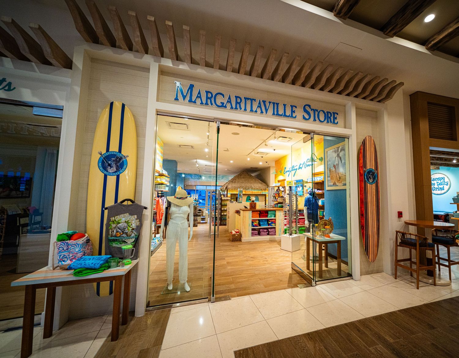 Margaritaville Store retail shop entrance featuring surfboard displays and tropical merchandise in a bright mall setting.