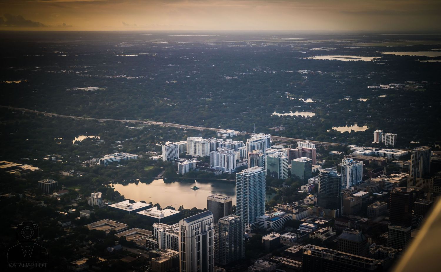 Sunset aerial view of urban development with high-rise buildings and infrastructure.