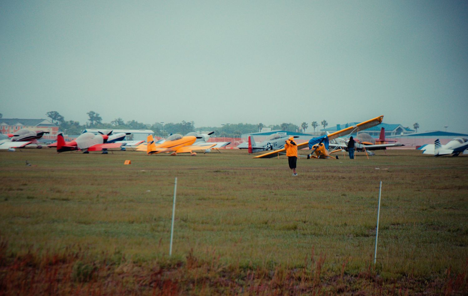 A series of hang gliders lined up on a grassy field during a competition or training event.