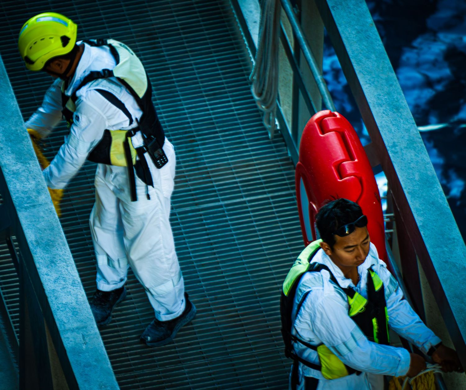 Aerial view of construction workers in yellow safety vests walking on scaffolding at a building site.