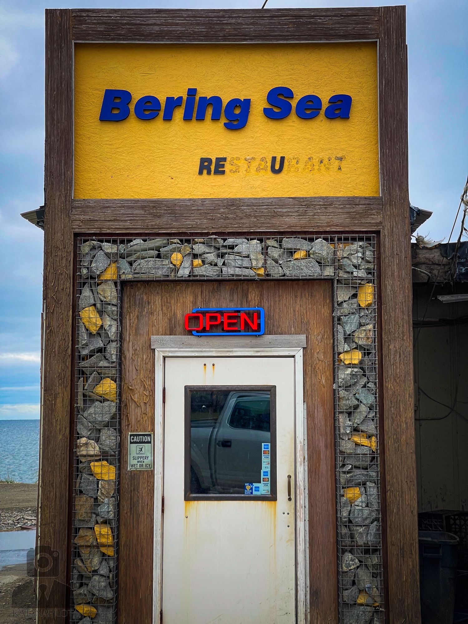 Exterior view of Bering Sea Restaurant with stone facade and wooden trim.