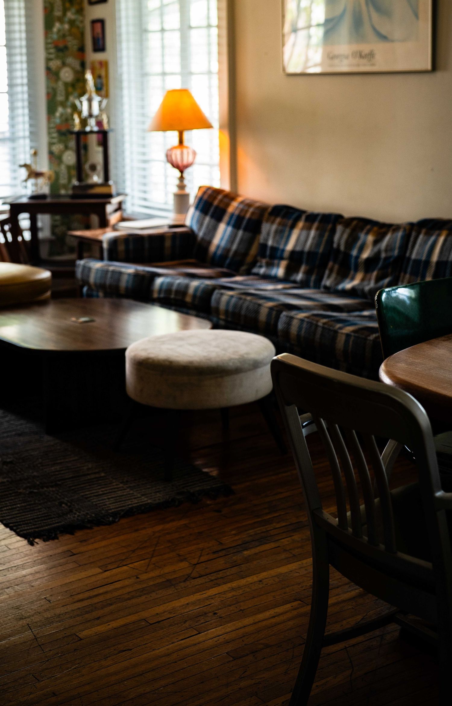 Dark wooden floor and seating area in a cozy bar with natural light streaming through windows.