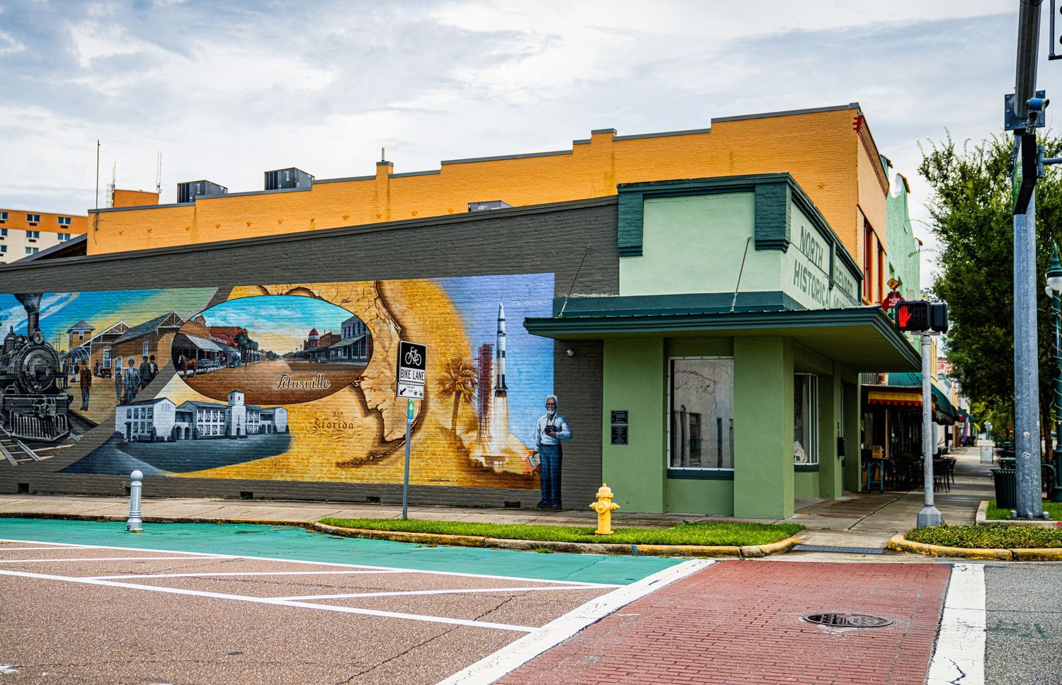 Colorful street corner building with vibrant mural art depicting a coastal scene.