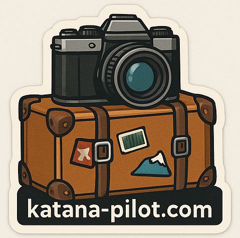 Vintage-style travel sticker showing a camera resting on brown luggage with mountain accents.