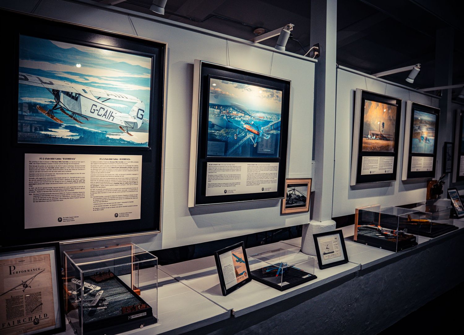 Aviation museum display cases showing historical aircraft artwork and informational plaques.