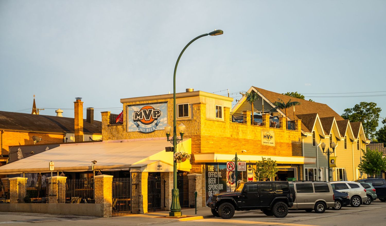 Row of yellow and tan commercial buildings lit by evening sunlight along a small town street.