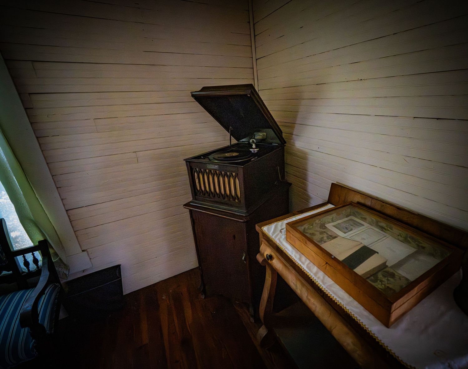 Dark interior room with wooden bench and historic artifacts on display.