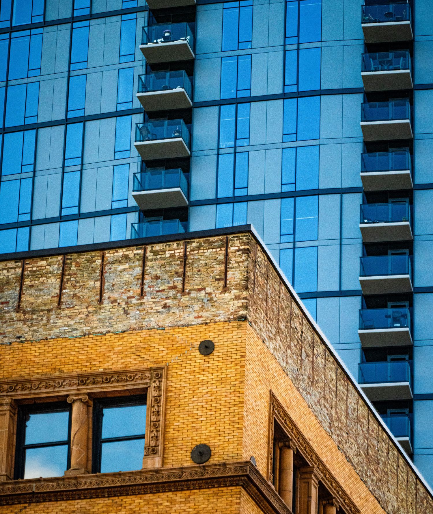 Modern glass high-rise building contrasting with historic brick architecture.