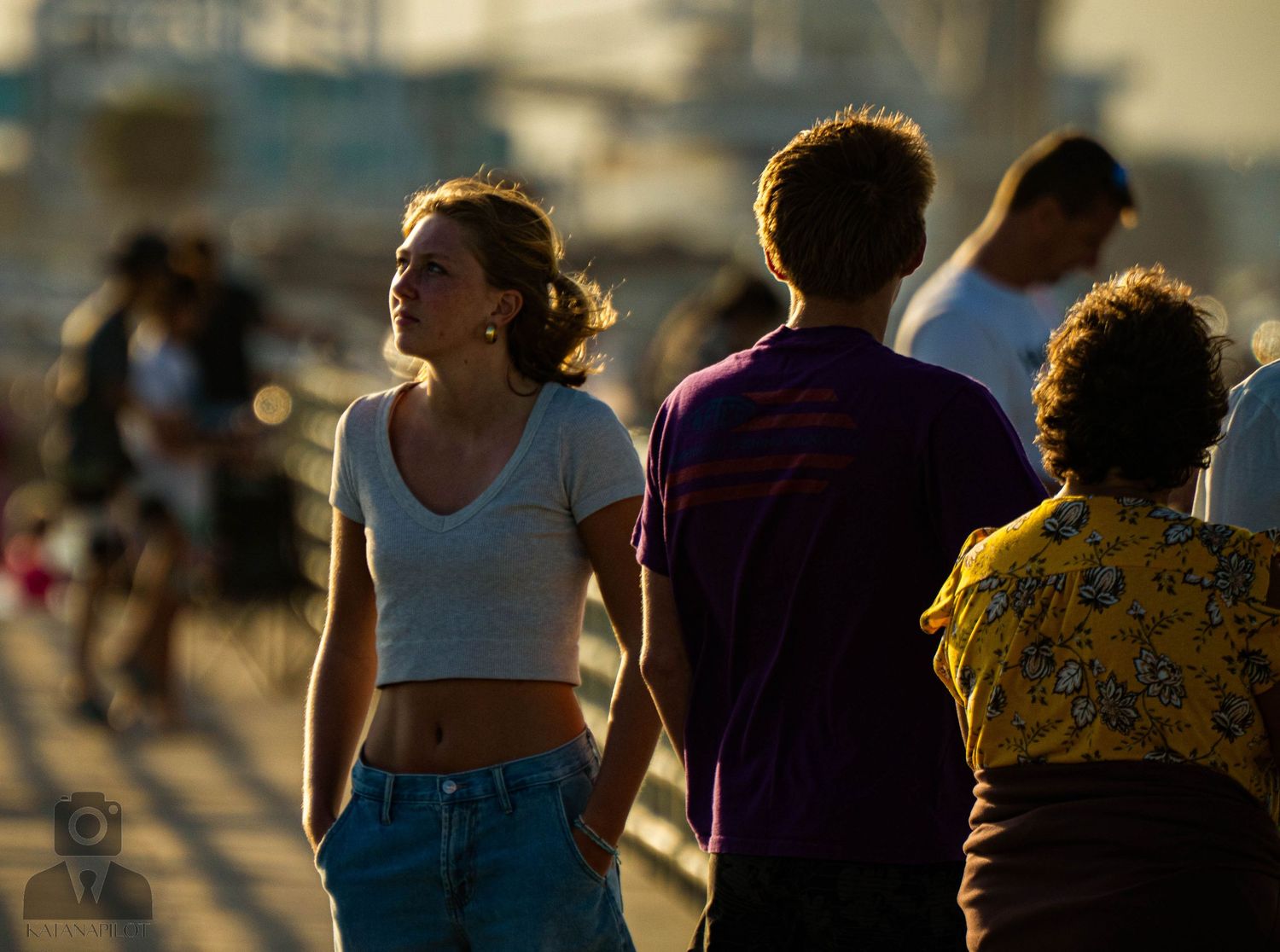 Group of people enjoying a sunset at the beach with silhouettes against golden light in the background.