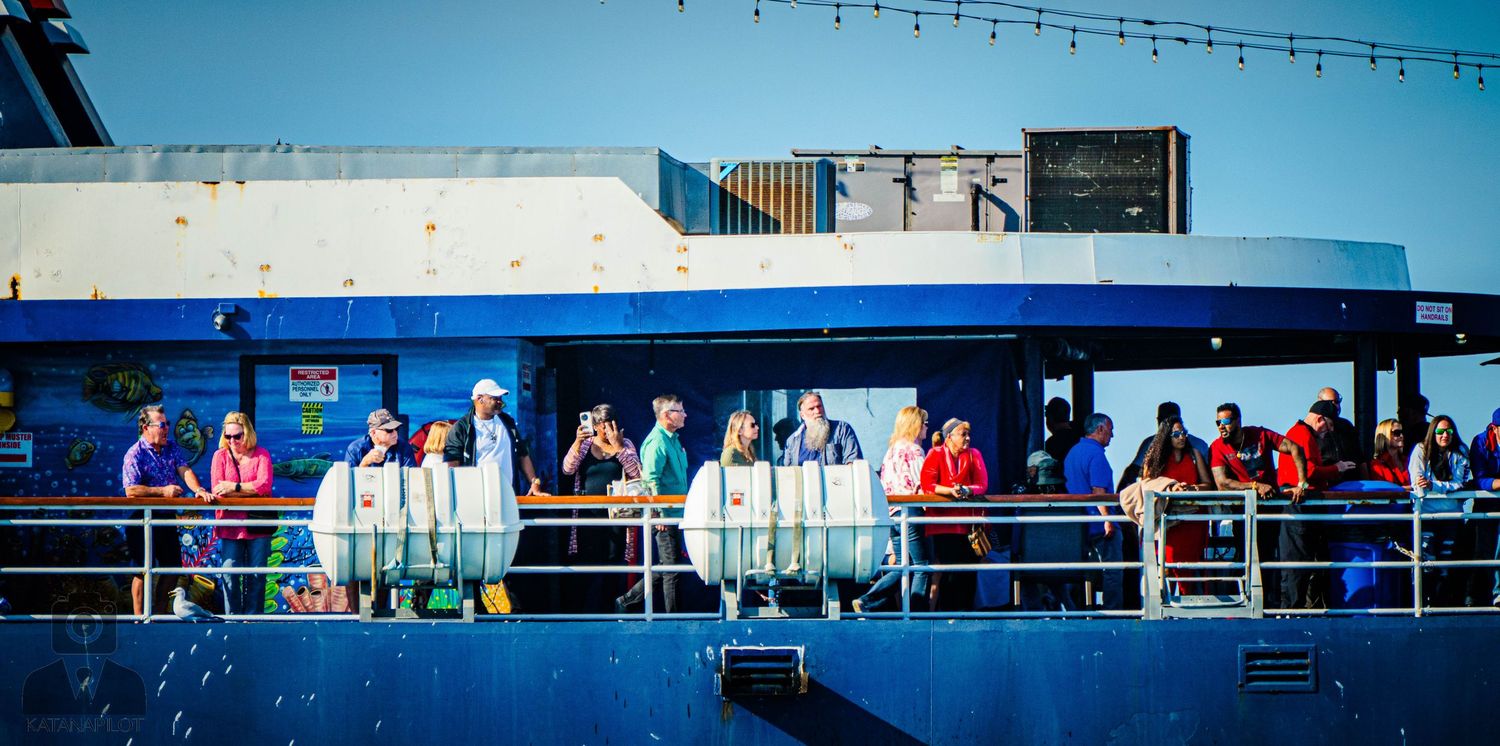 Spectators watch a sporting event from multiple levels of outdoor stadium seating on a sunny day.