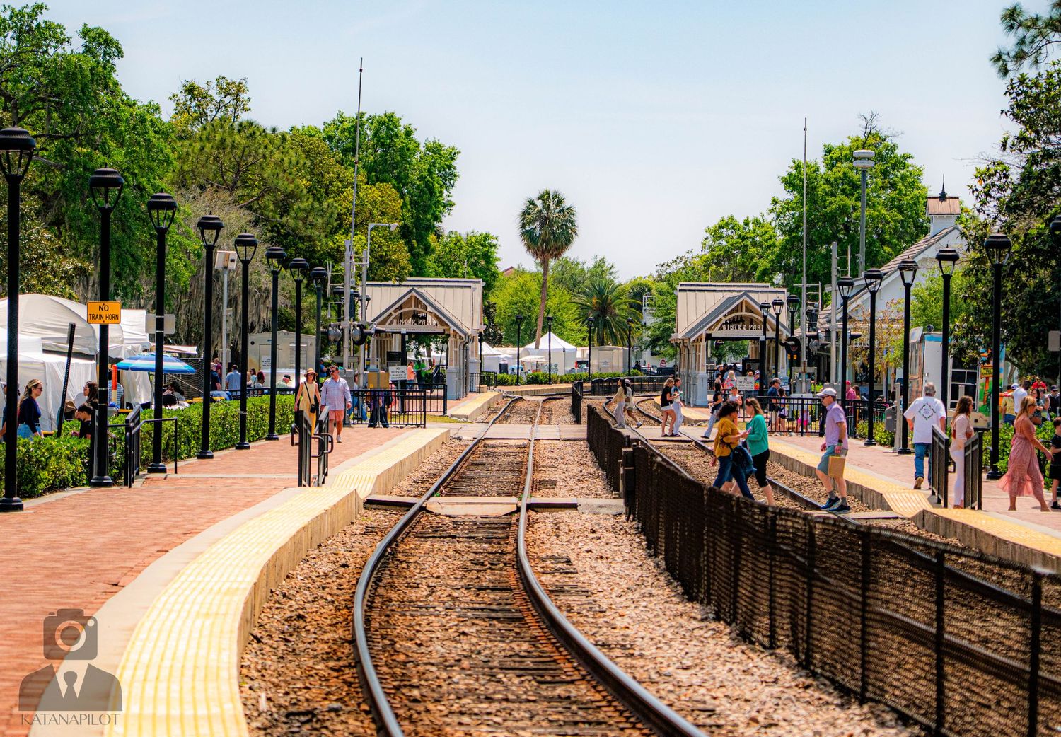 Train tracks and platform stretching into the distance with trees lining both sides.