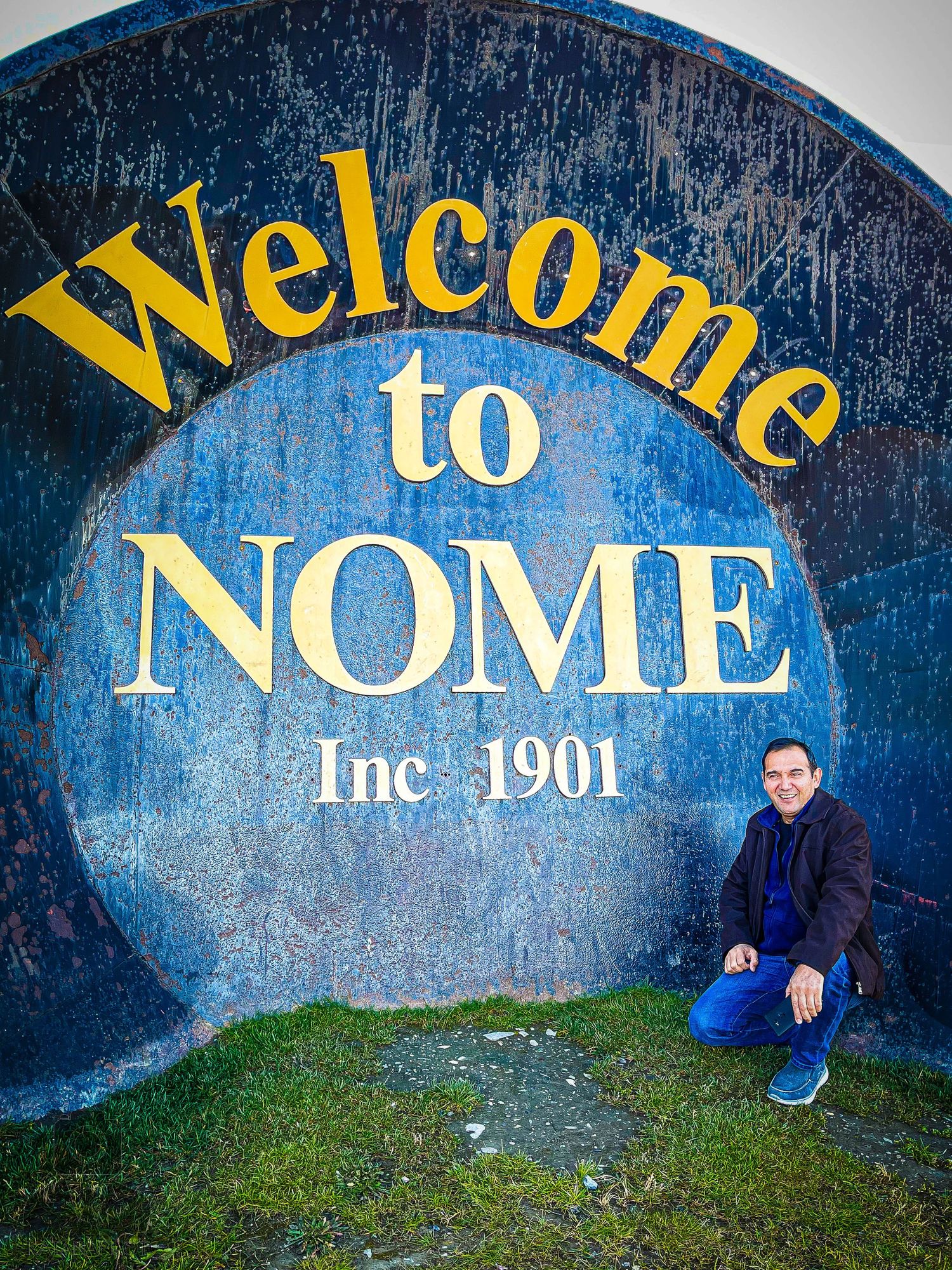 Welcome to Nome sign painted in yellow and white on a blue wall dated 1901.