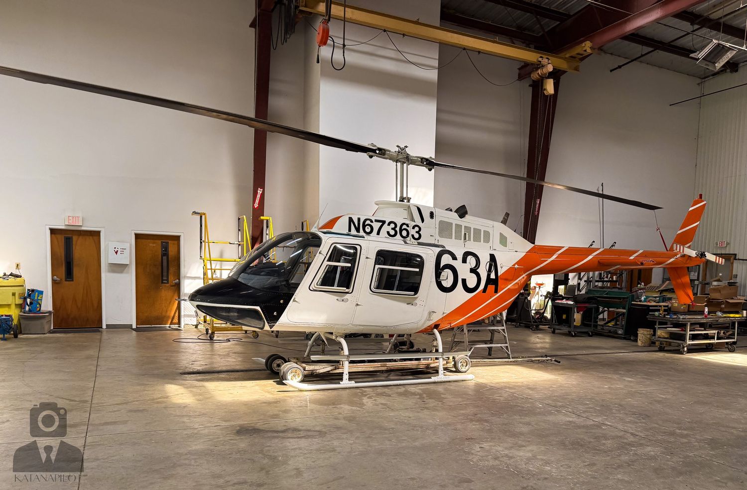 Interior of an aircraft hangar showing multiple helicopters and small aircraft stored inside.